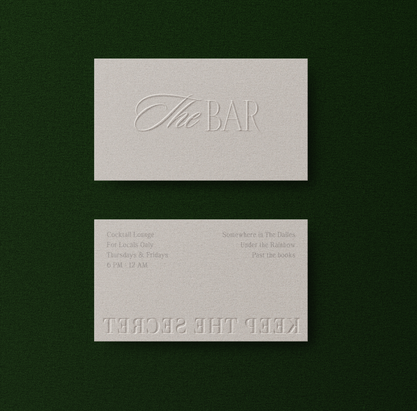 Two beige business cards with embossed text on a dark green background. The top card reads "The BAR" in elegant script. The bottom card has embossed text that is partially visible, including words like "KEEP THE SECRET" and details about a cocktail lounge open Thursday and Friday from 6 PM to 12 AM.