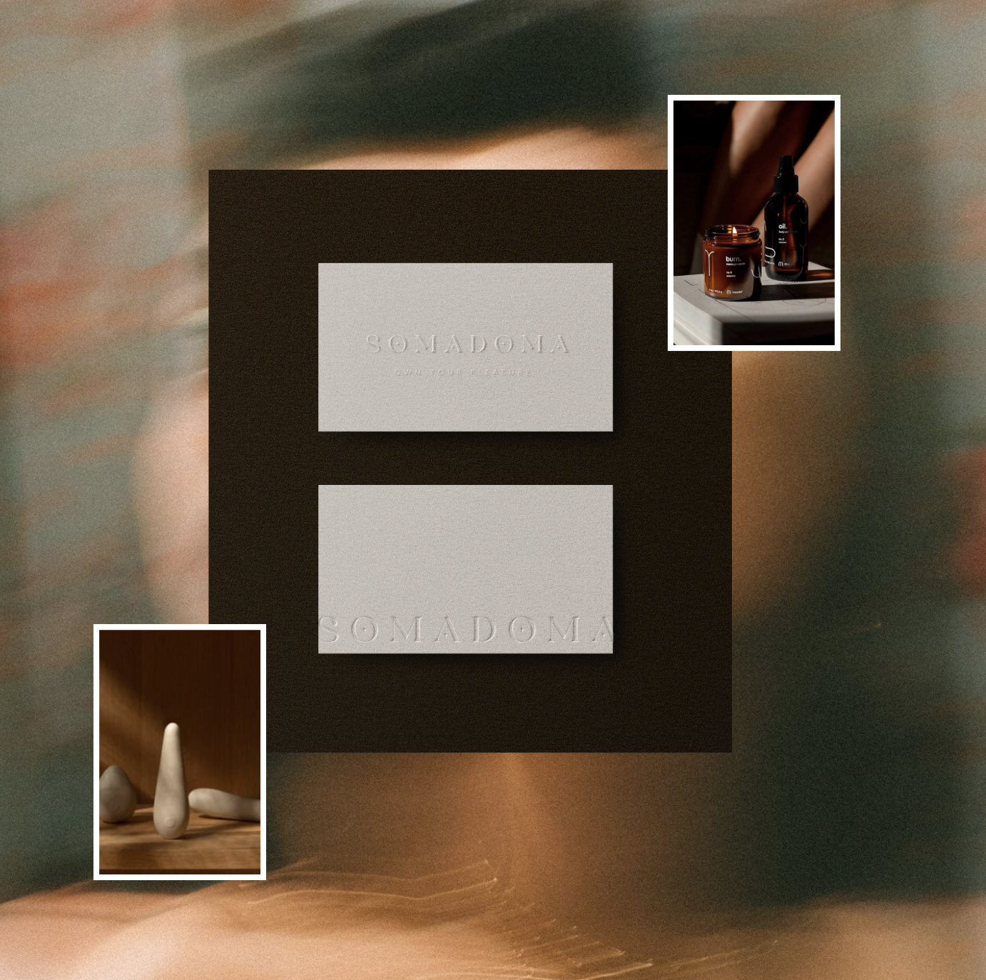 A flat lay of two white embossed cards with the word 'SOMADOMA,' placed on a dark square surface. Two smaller inset photos show skincare products in amber and black bottles on the top right, and ceramic decorative objects in neutral tones on the bottom left.