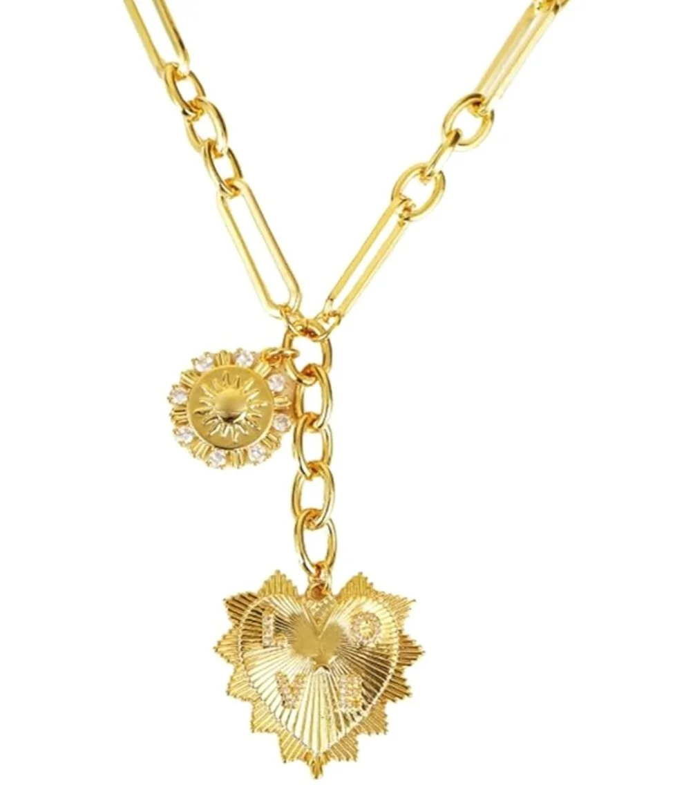 Gold jewelry chain with two pendant charms, one with a sun design and the other with a lion's head, both adorned with small gemstones.