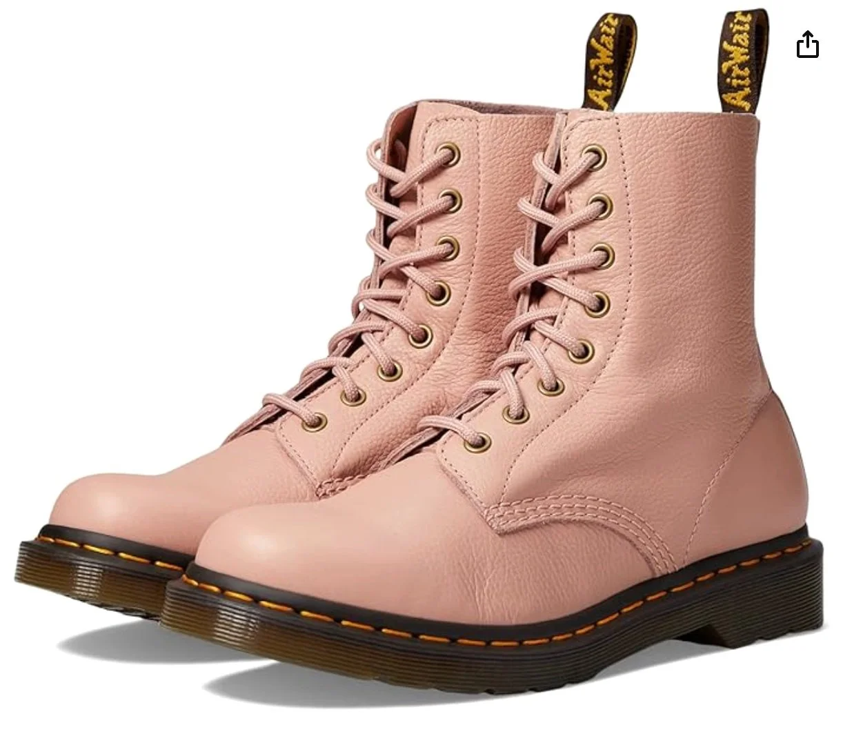 A pair of pink leather lace-up boots with black soles and yellow stitching, featuring black and yellow pull tabs with the text 'AirWair'.