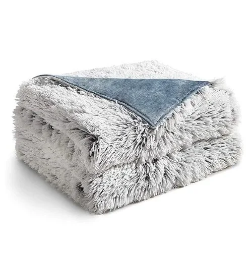 A soft, fluffy gray pet bed with a cushioned base and raised sides, featuring a darker gray blanket or cover on top.
