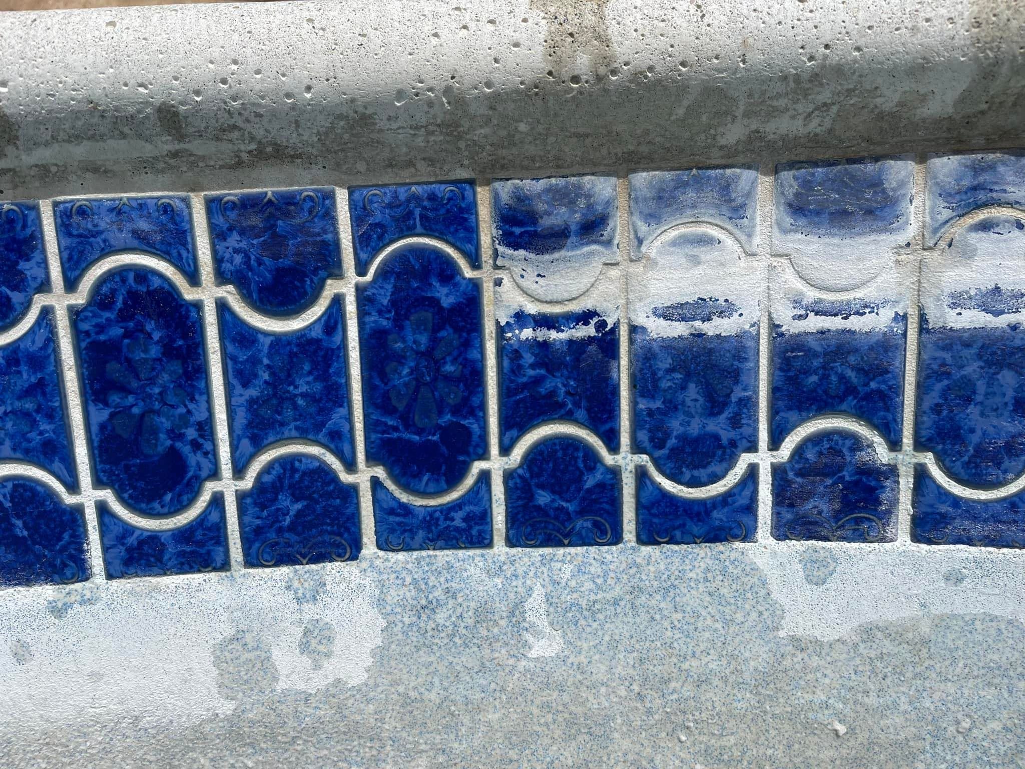 Close-up of a decorative blue tiled border with white grout, partially covered in water and soap.