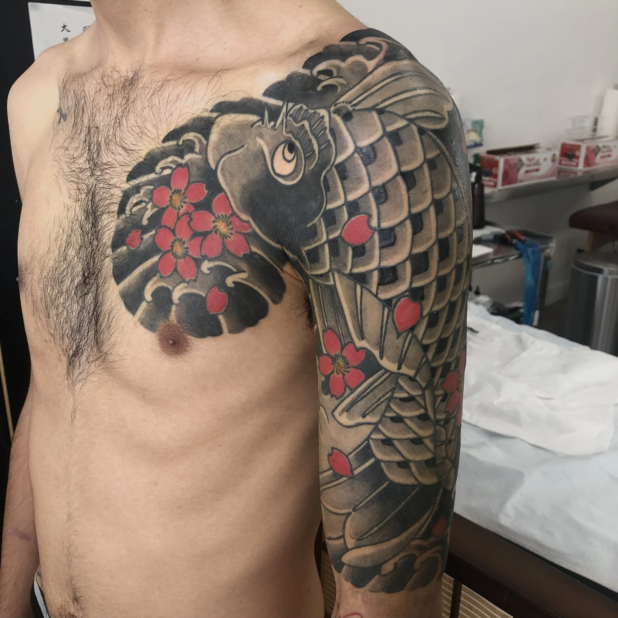 Tattoo of a large, stylized snake with red flowers on the upper arm and shoulder.
