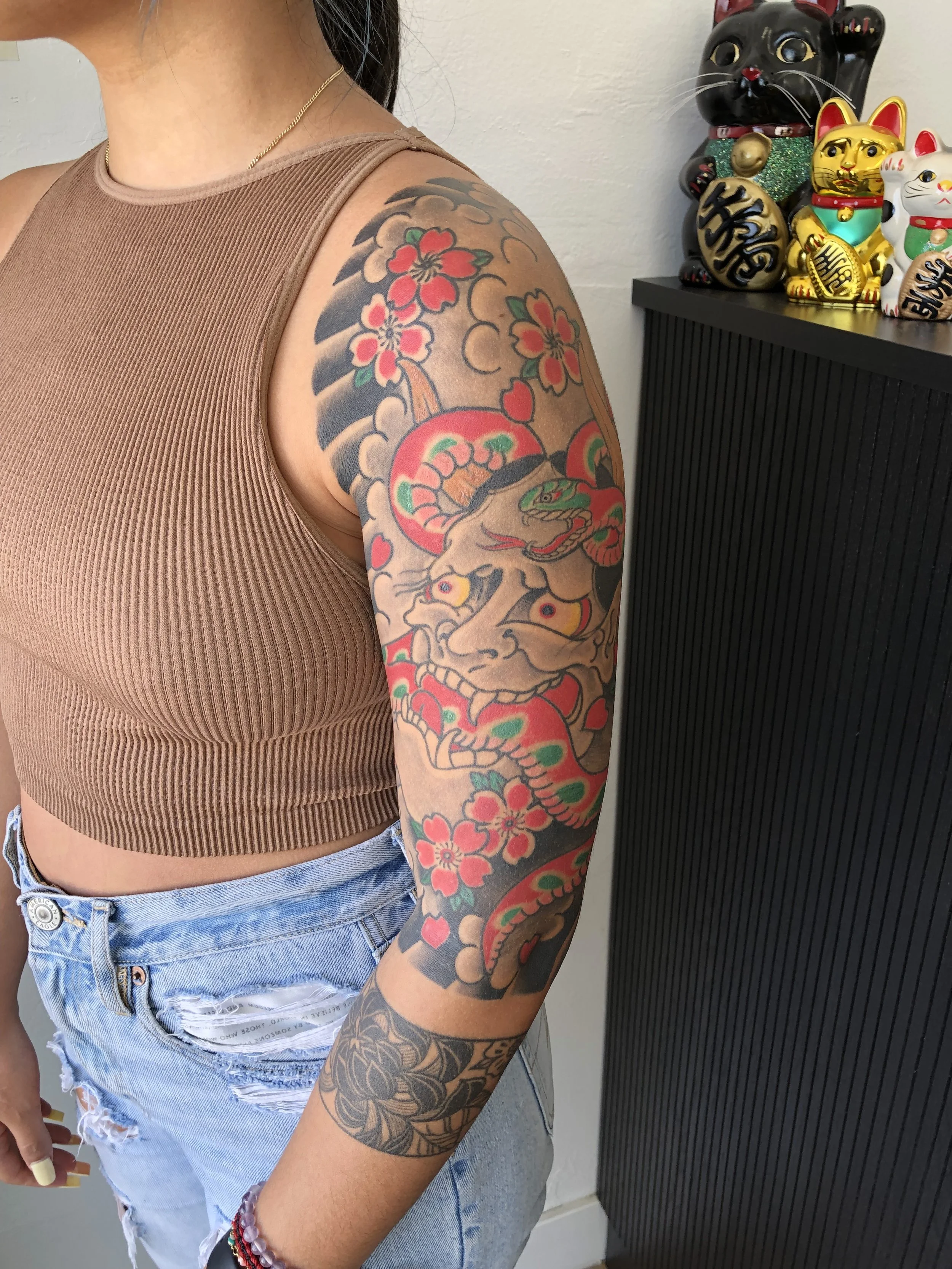 Tattoo sleeve featuring a traditional Japanese style dragon and cherry blossoms on a person's upper arm.