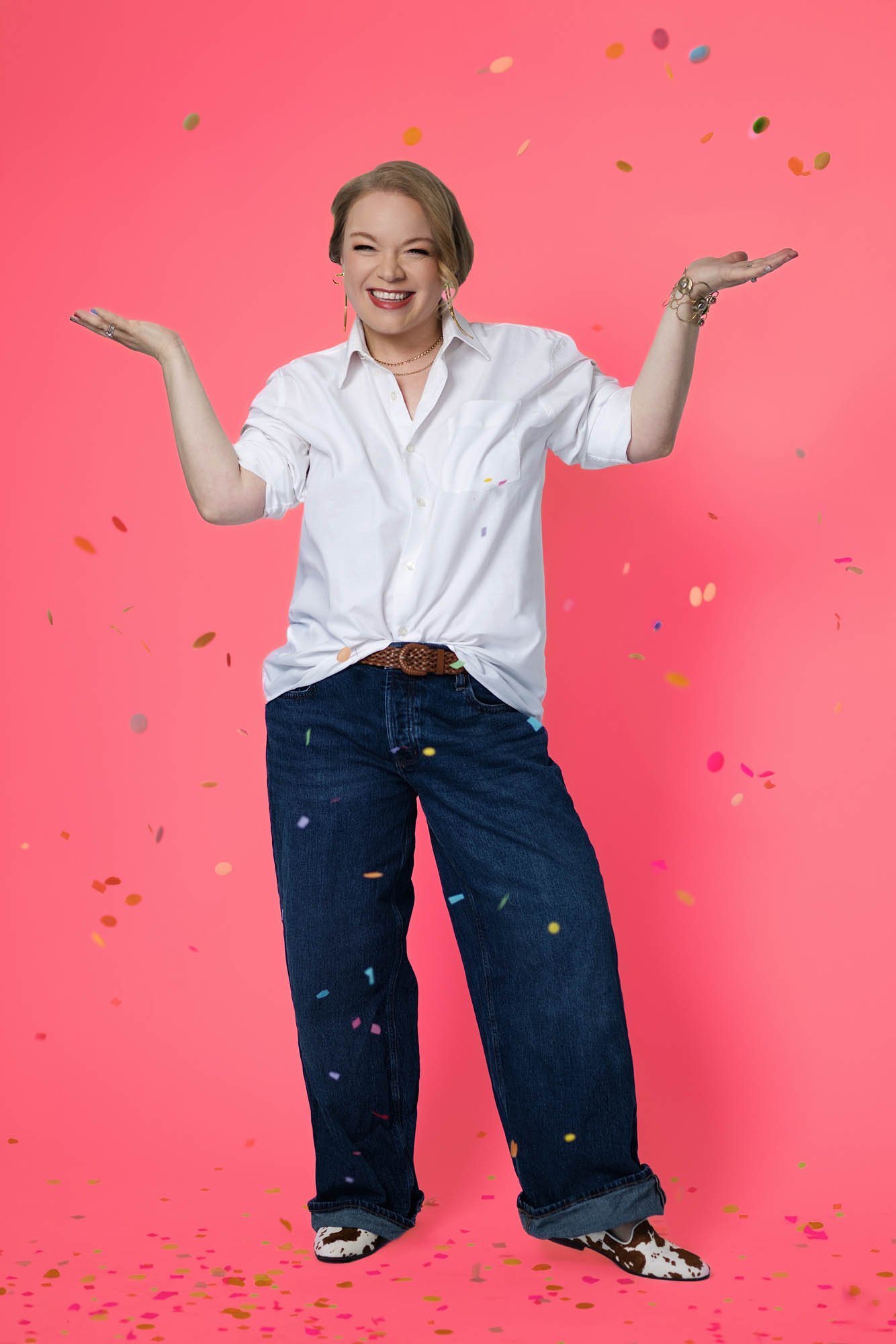 Jessie Hemmelgarn celebrating her business, smiling, standing against a pink background, with multicolored confetti falling around her.