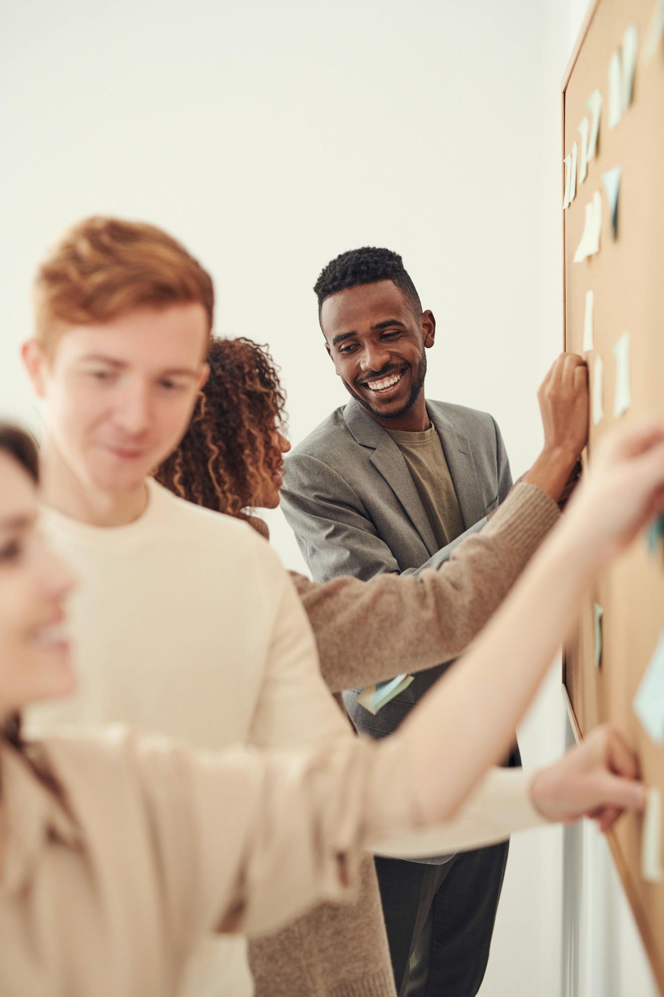 People working together placing sticky notes on a wall in an office or classroom setting.