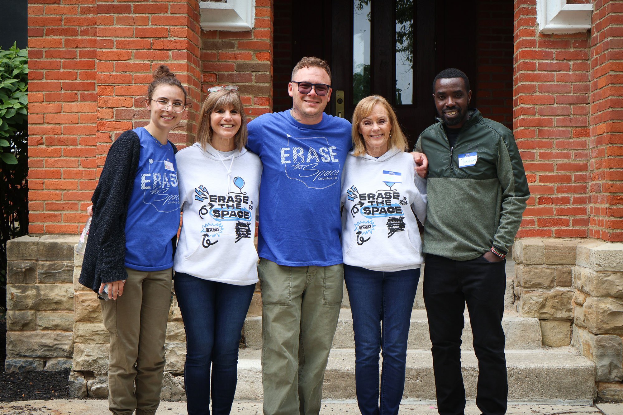 Members of the Erase the Space community stand together outside a brick building, reflecting unity, collaboration, and shared purpose.