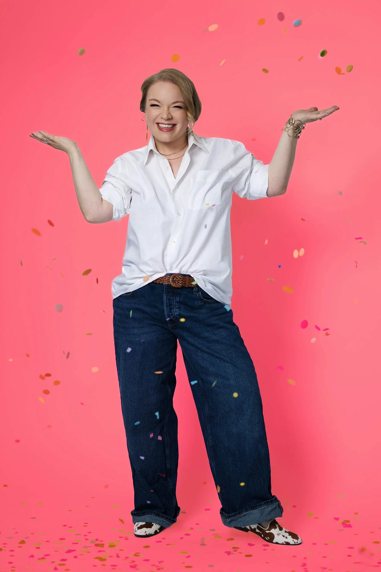Jessie Hemmelgarn celebrating her business, smiling, standing against a pink background, with multicolored confetti falling around her.