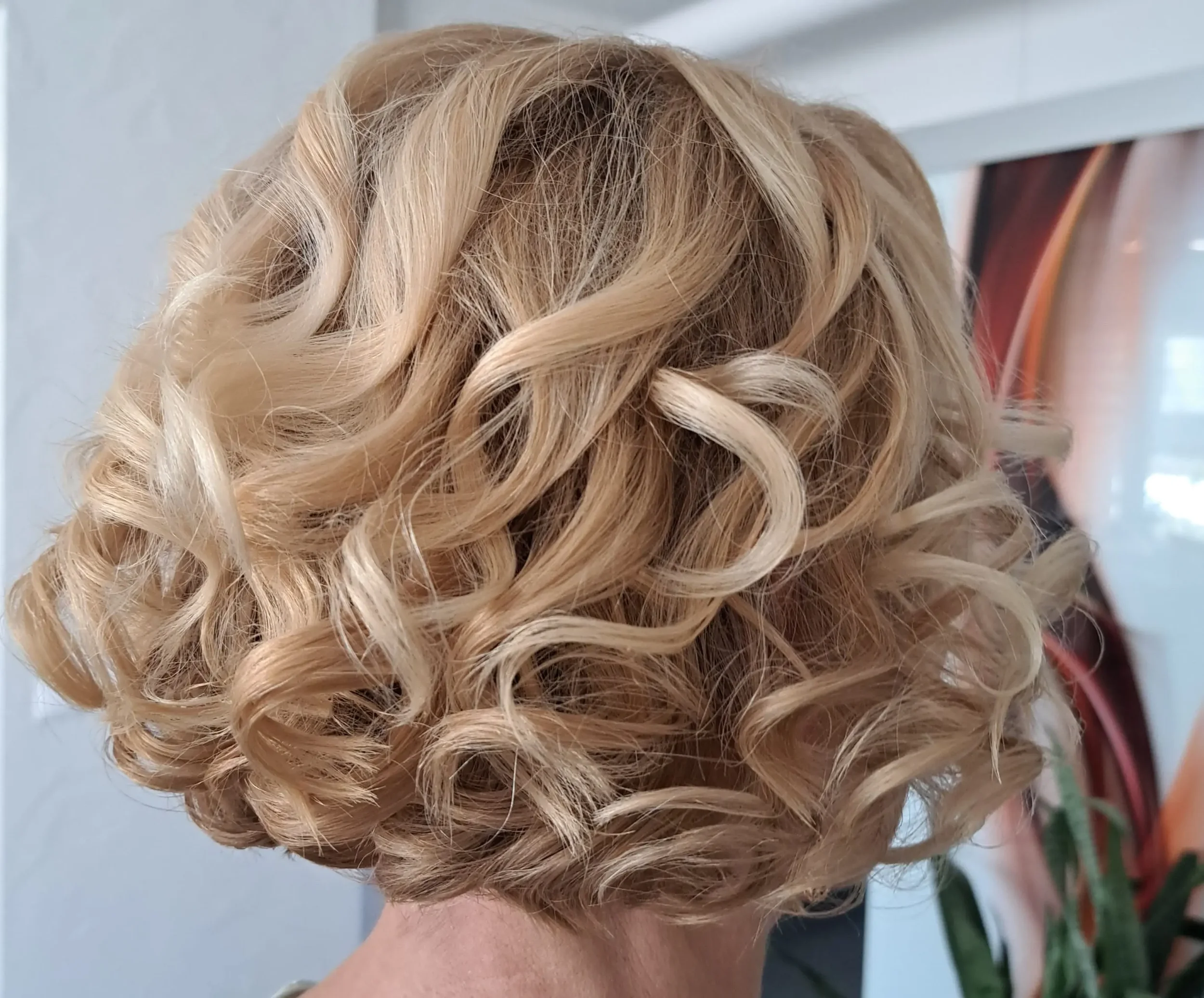 Trumpų šviesių garbanotų plaukų šukuosena grožio salone „Edita“.