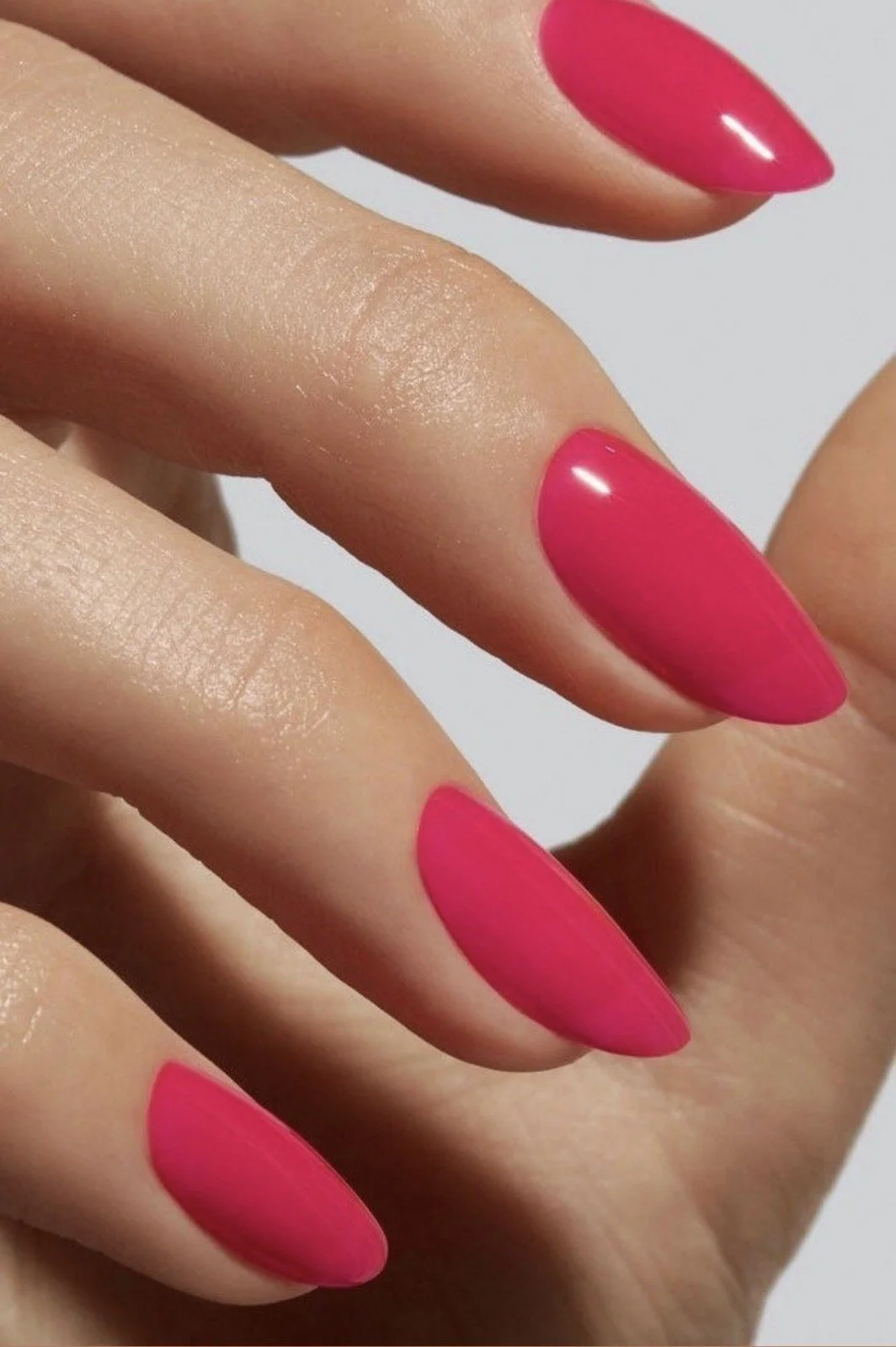 Ryškiai rožinis ilgų migdolo formos nagų manikiūras salone „Edita“.