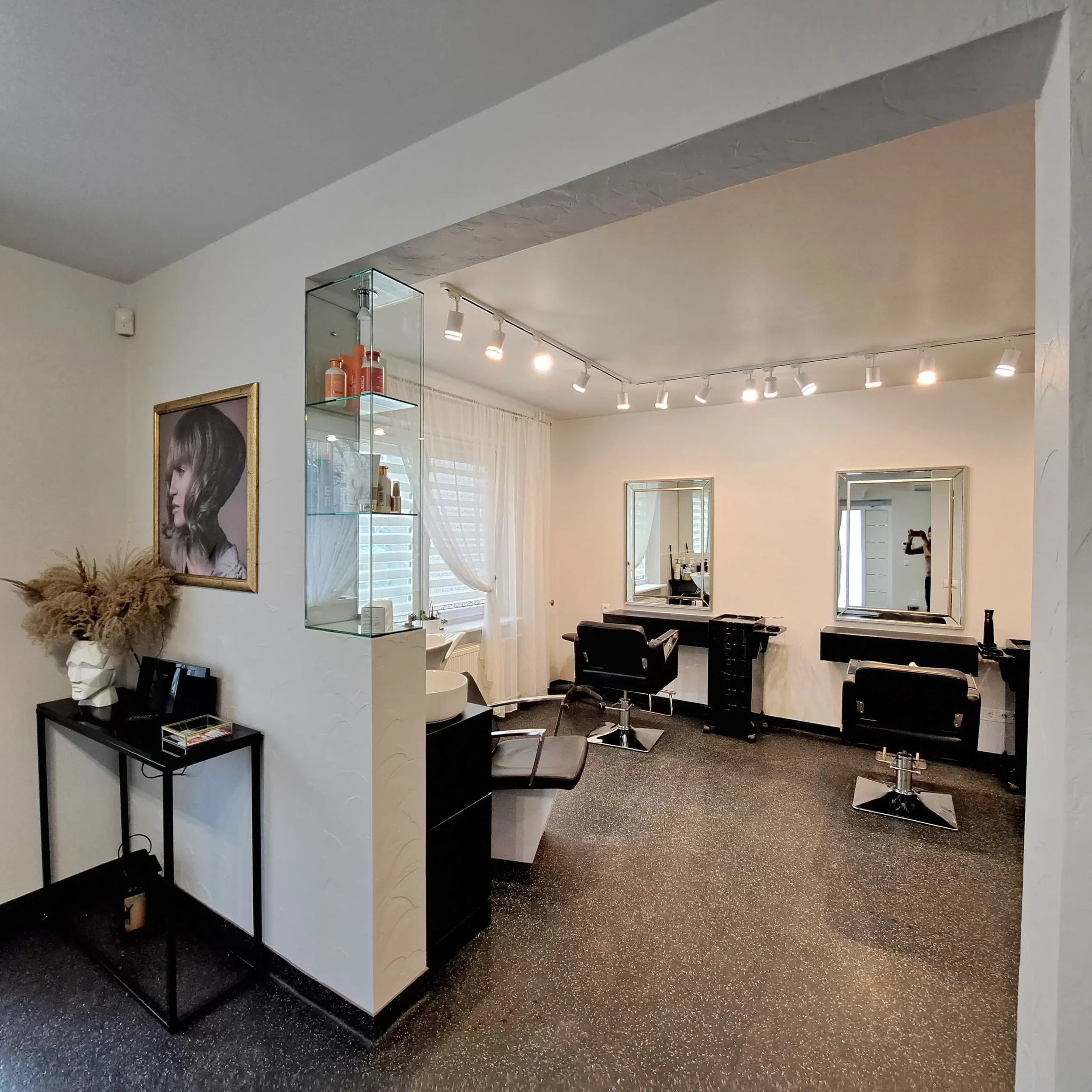 Modernus ir šviesus grožio salono „Edita“ interjeras su kirpėjų darbo vietomis.