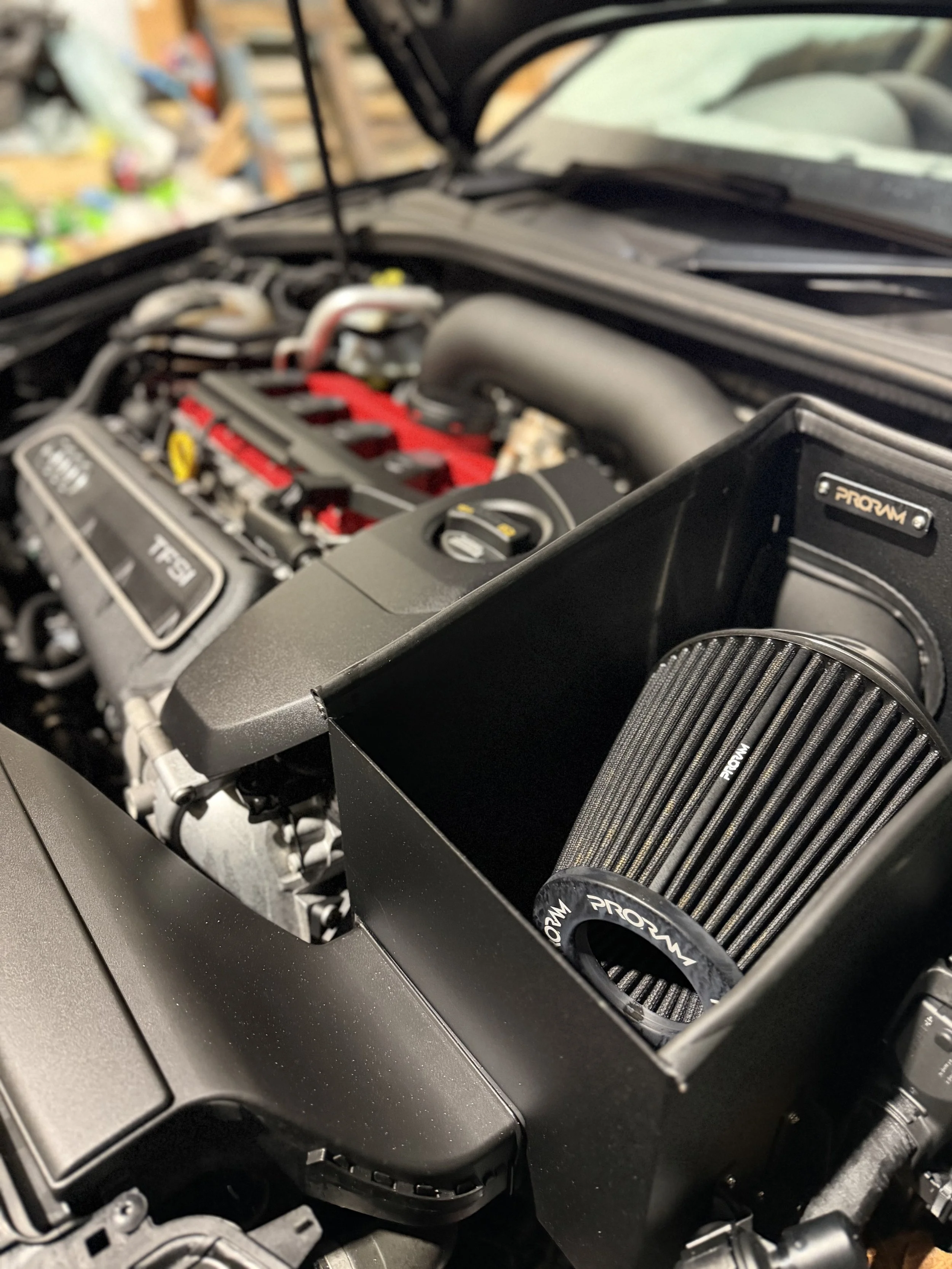 Car engine with cold air intake installed, featuring a ProM high-flow air filter in a black intake box.