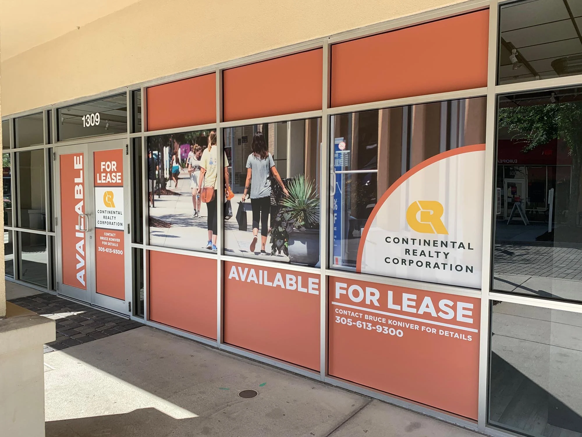 Storefront with large windows displaying 'Available for Lease' signs for Continental Realty Corporation, with contact details, and a busy sidewalk scene with pedestrians walking.