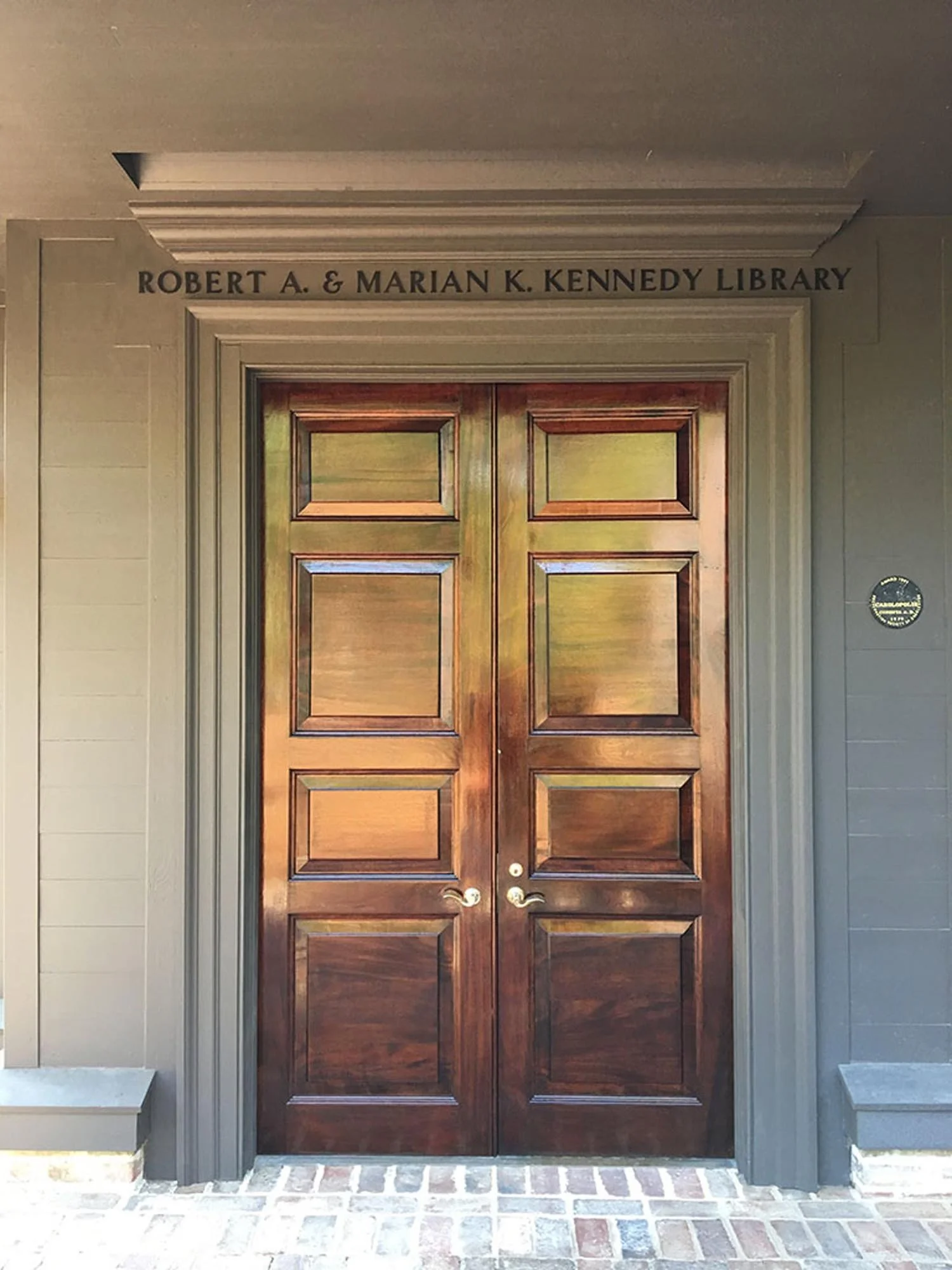Double wooden doors inside a building labeled 'Robert A. & Marian K. Kennedy Library' at the top.