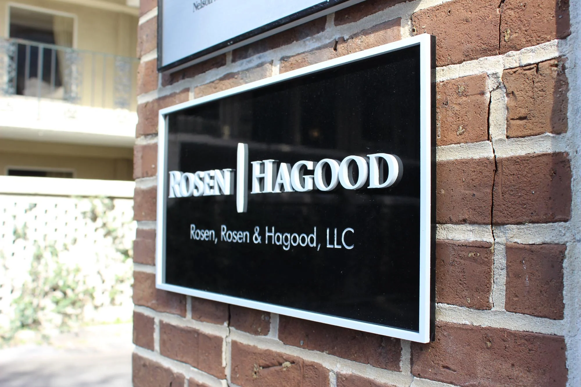 Black and white business sign reading "ROSEN | HAGOOD" with smaller text "Rosen, Rosen & Hagood, LLC" mounted on a brick wall.