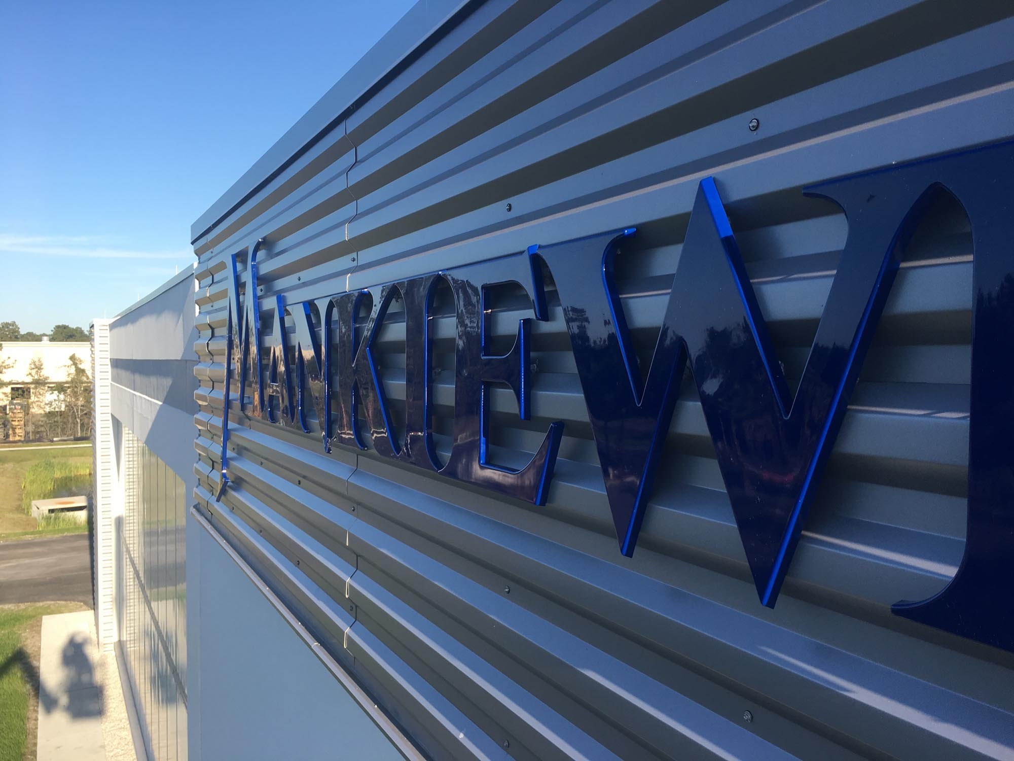 Close-up of a building's exterior wall with metallic horizontal panels and a blue 3D sign that reads 'Wackley W'
