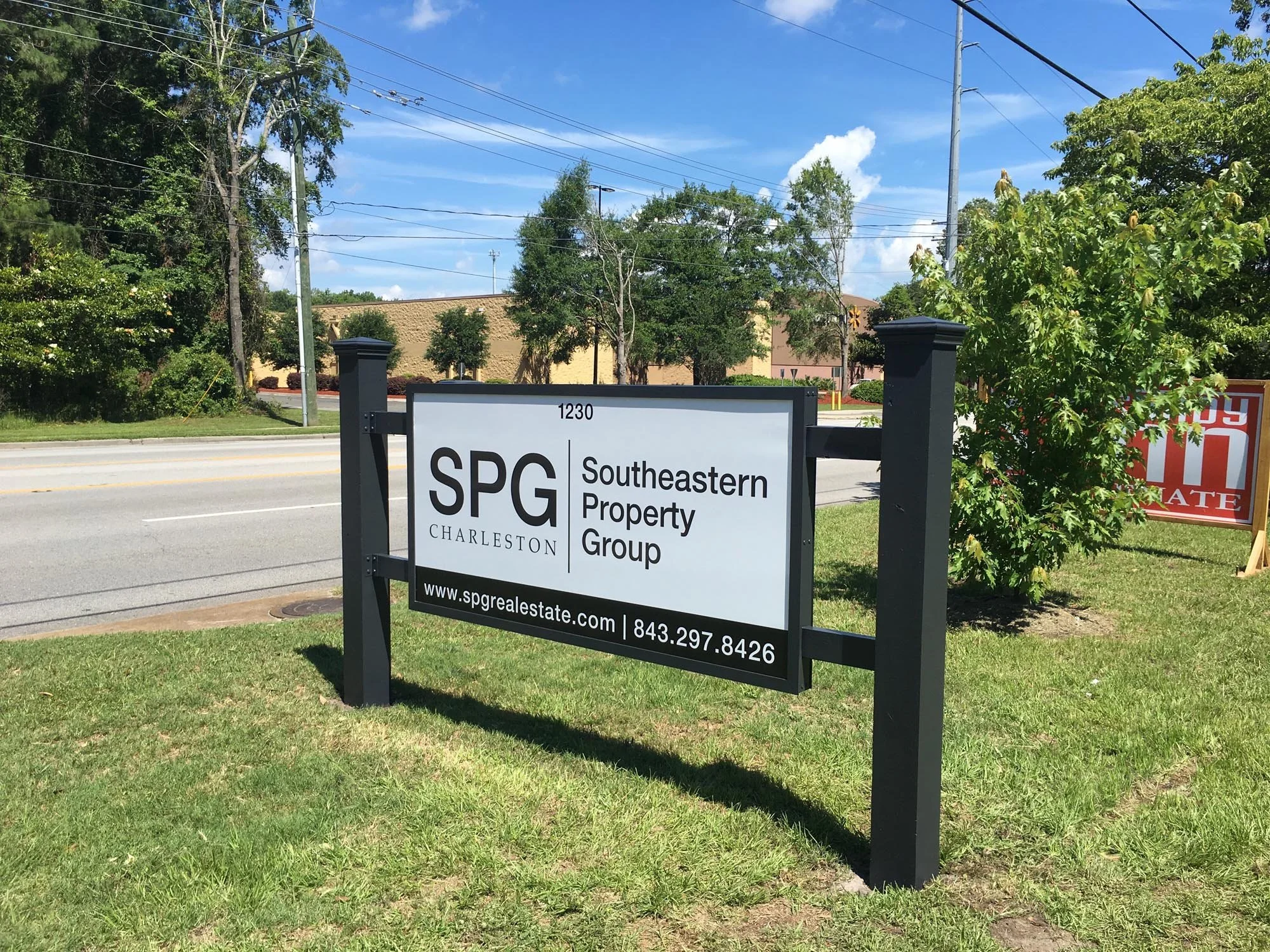Sign for Southeastern Property Group in front of a grassy area near a road with trees and power lines in the background.