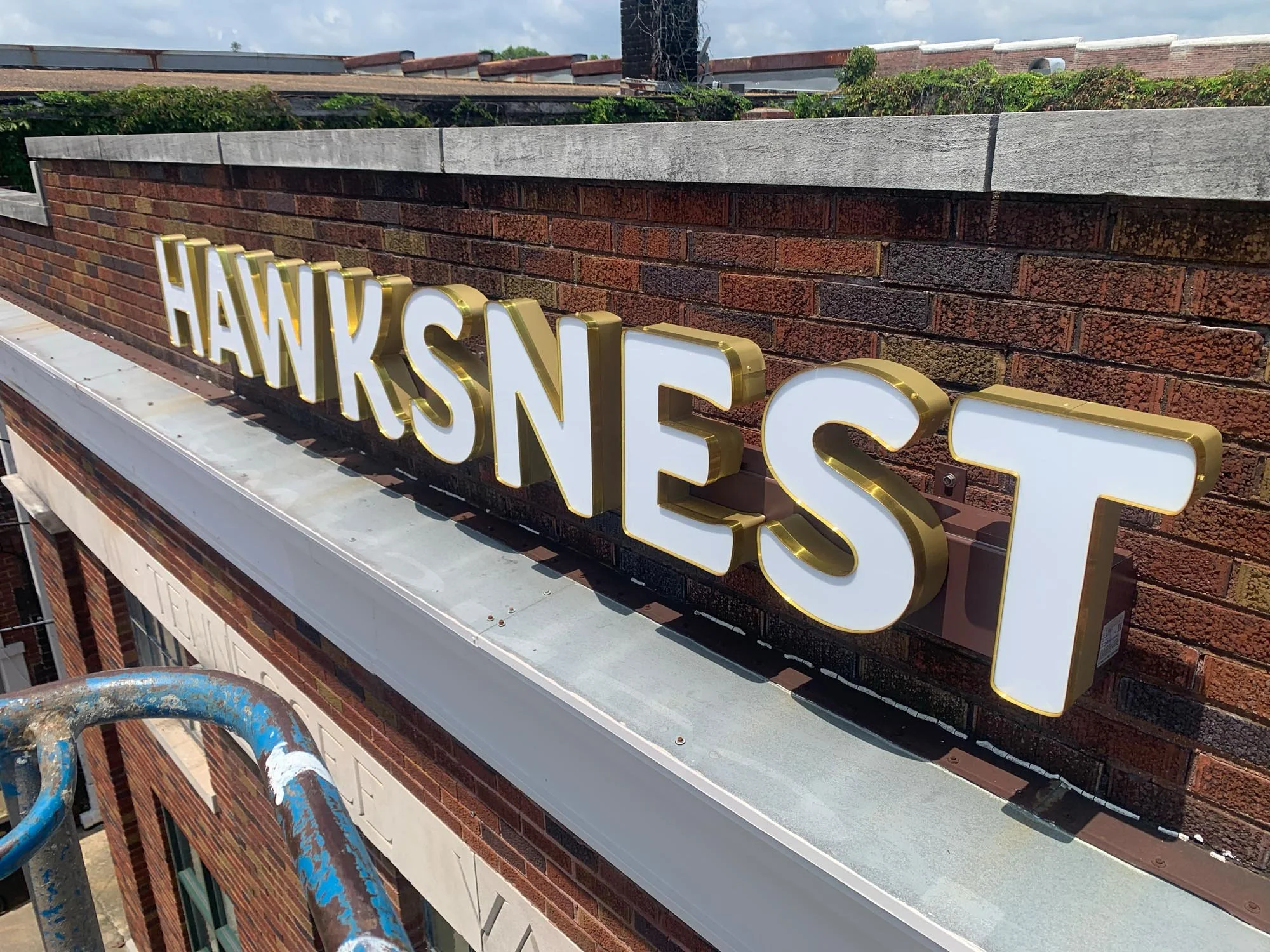 A neon sign spelling 'HAwaksnest' on a brick building exterior. Channel letters