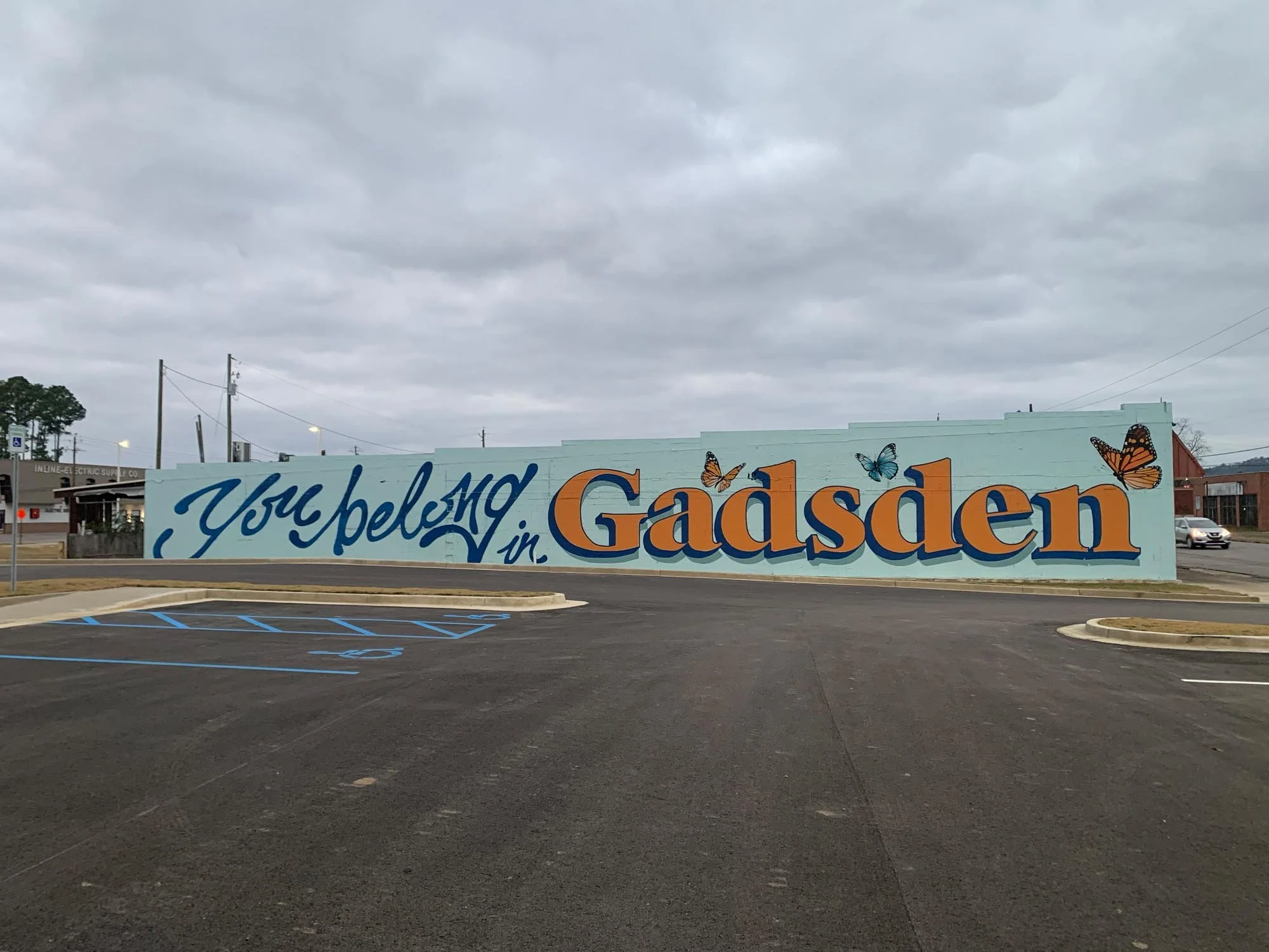 Large painted mural on a wall saying 'You belong in Gadsden' with butterflies.