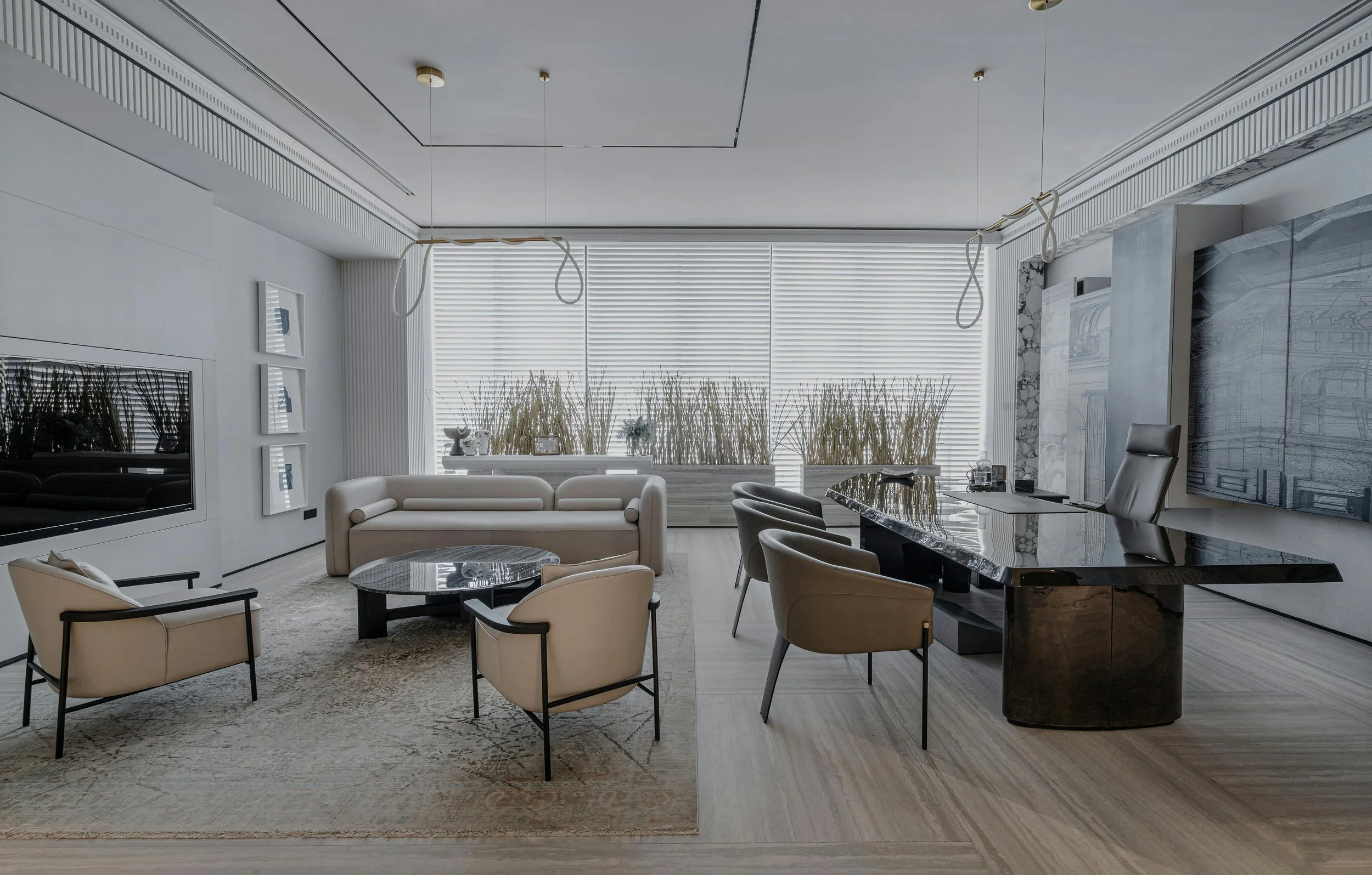 Modern office with a large black marble desk, beige chairs, a beige sofa, a wall-mounted TV, and large windows with blinds and decorative plants.