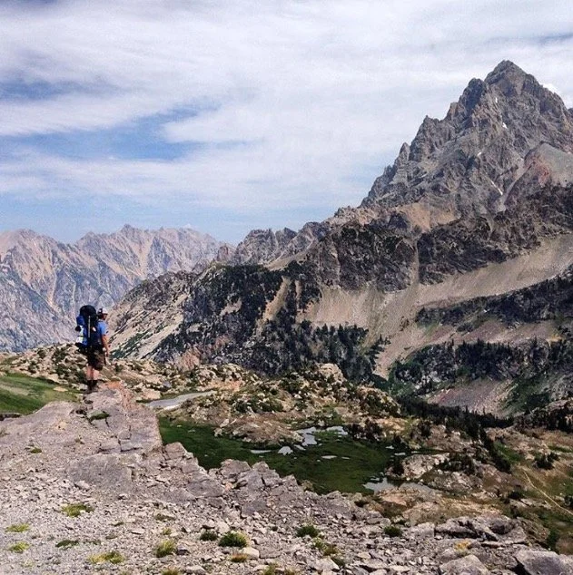 Mountain scene with sole hiker staring thoughfully into the distance
