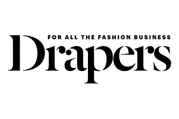 Silhouette of a city skyline at sunset with dark buildings against an orange sky.