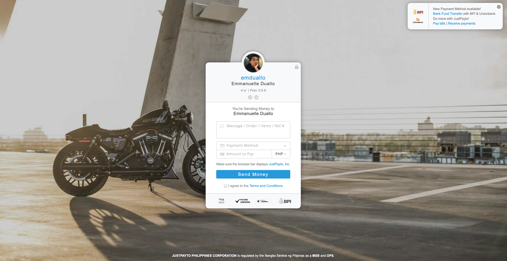 A black motorcycle parked on top of a parking lot with a concrete pillar in the background and city buildings in the distance during sunset.