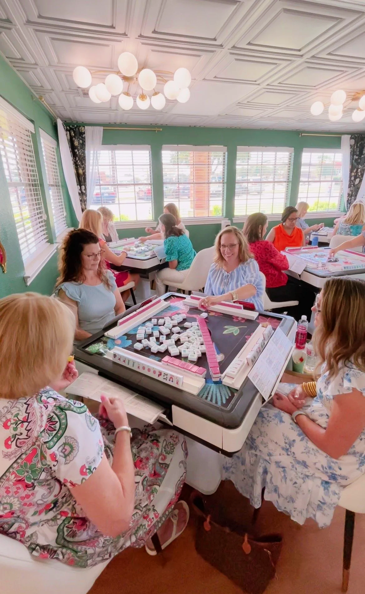 women sitting around automatic mahjong tables and playing