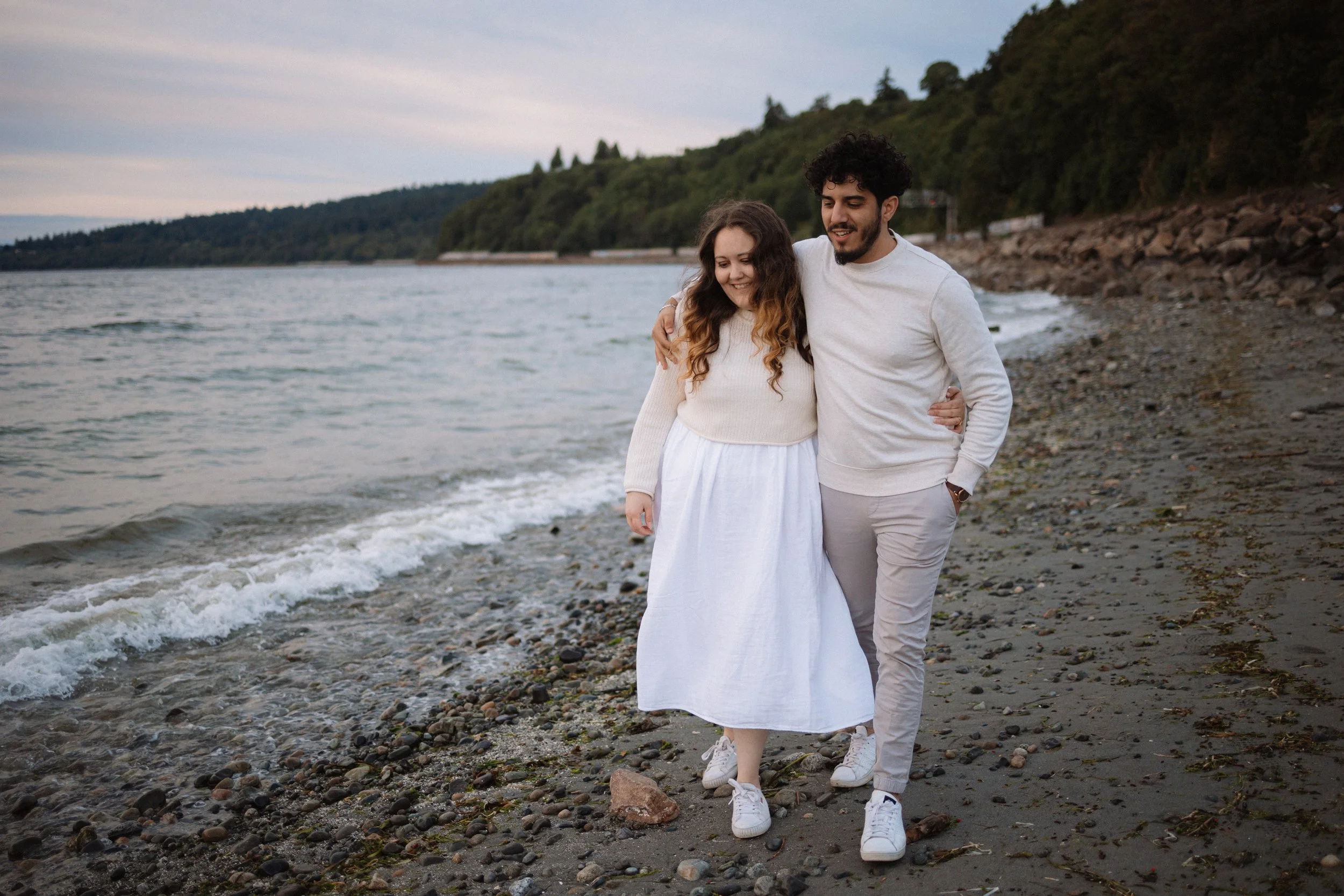 A couple photoshoot at Carkeek Park, Seattle. Couple walking by the water and hugging.