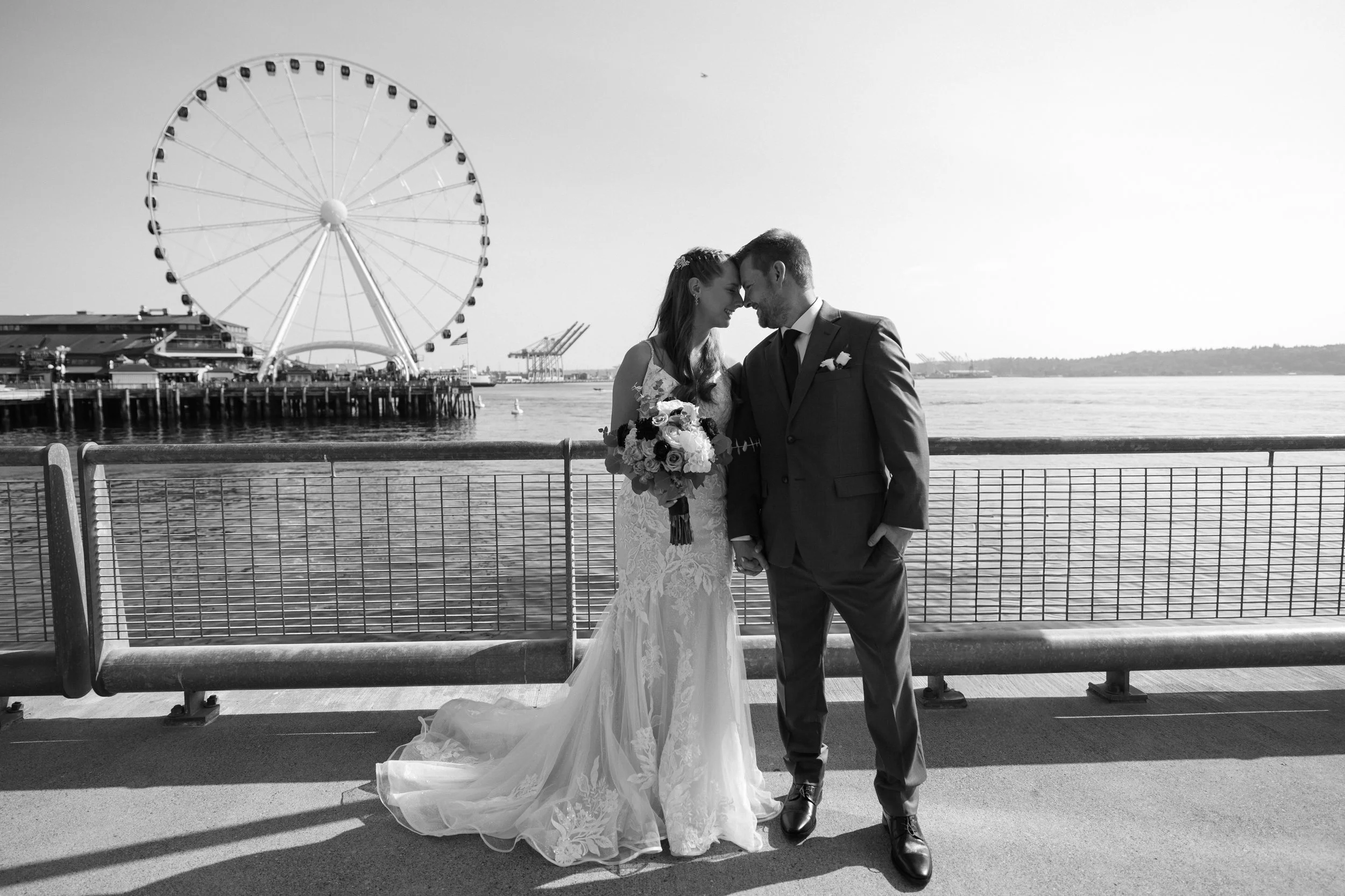 Black and white wedding couple portrait on the Seattle waterfront with the Seattle Great Wheel in the background.