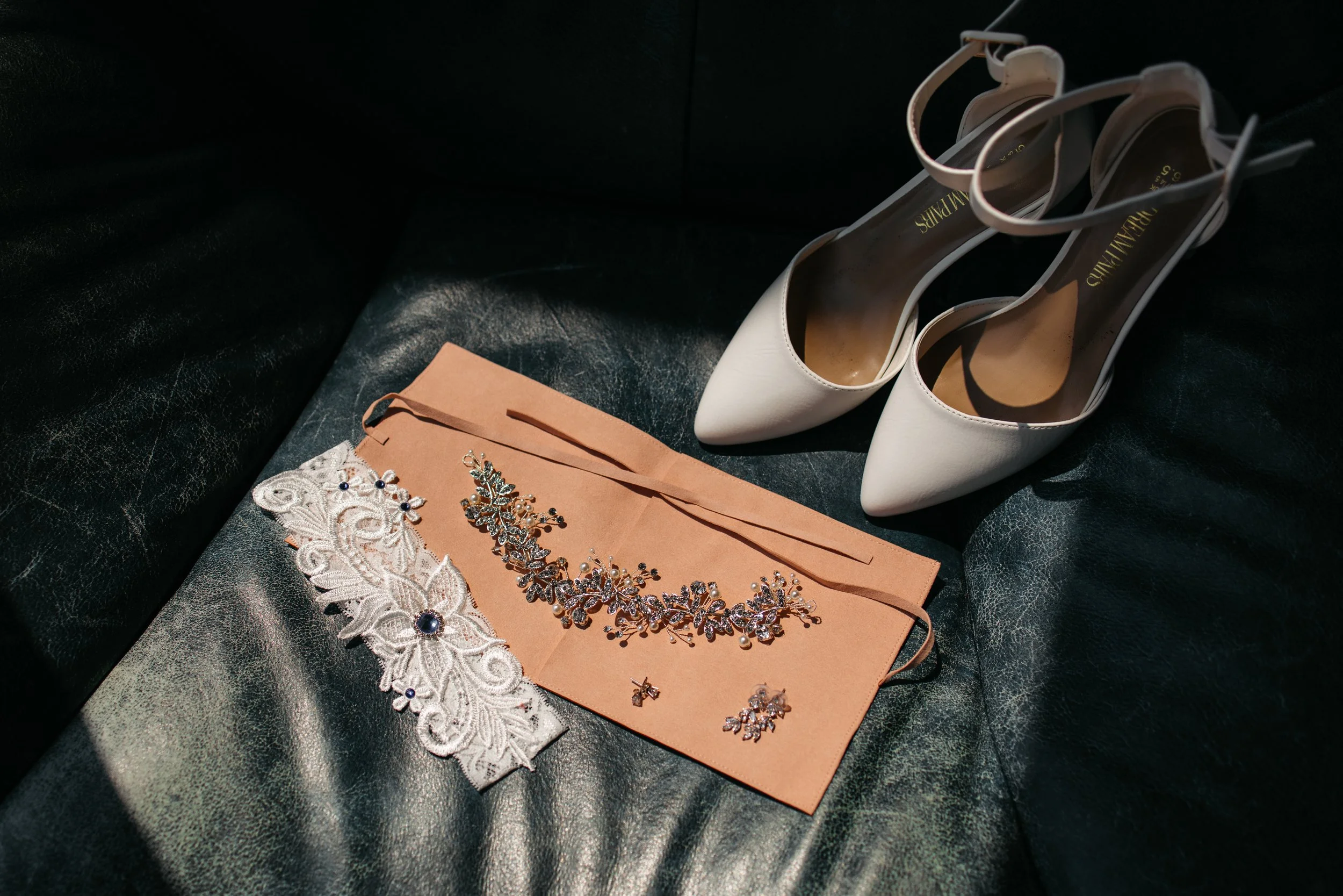 Bridal details including shoes and jewelry photographed during wedding preparation.