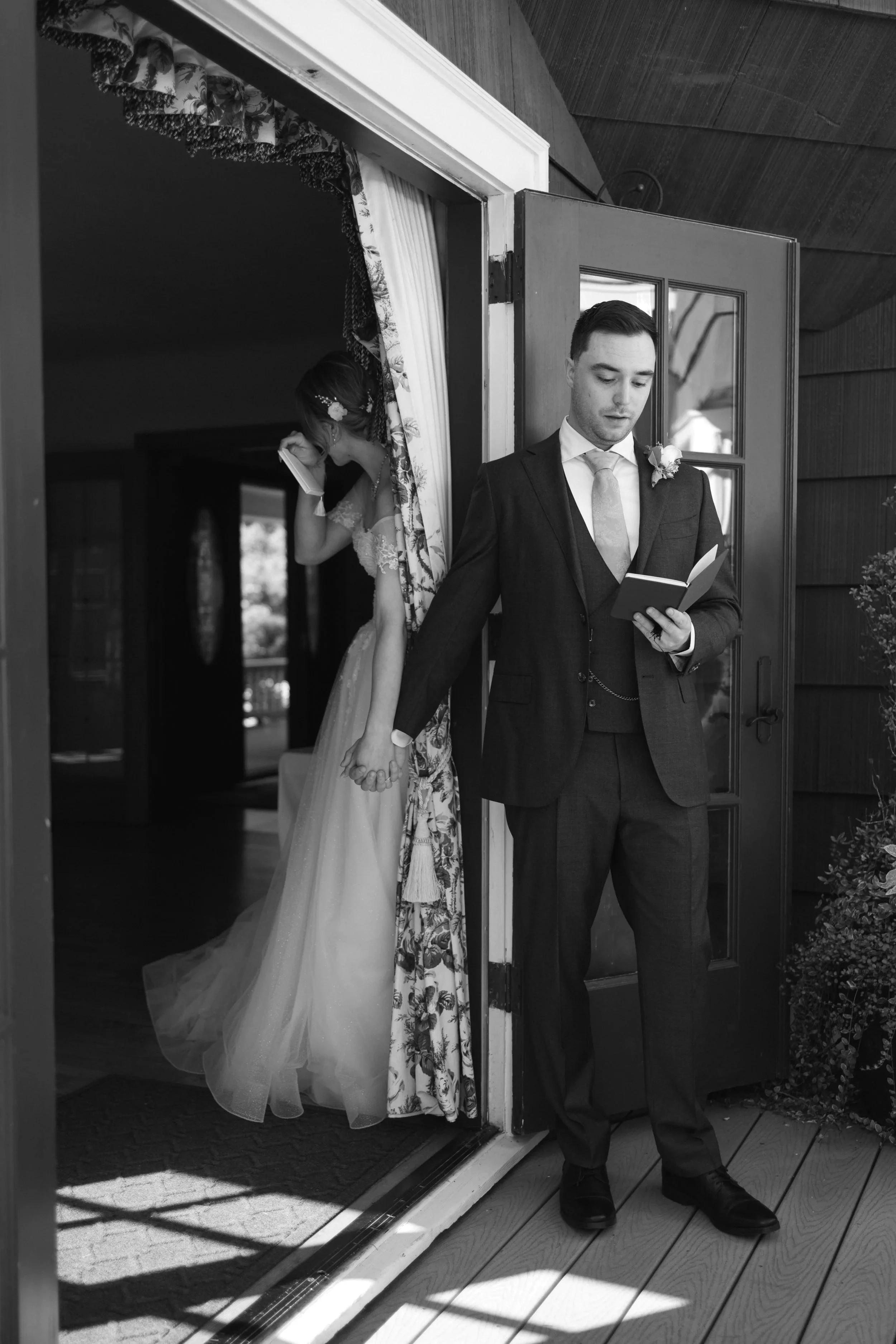 A groom , holding a bride's hand during reading their private vows before the ceremony at Laurel Creek Manor wedding venue.