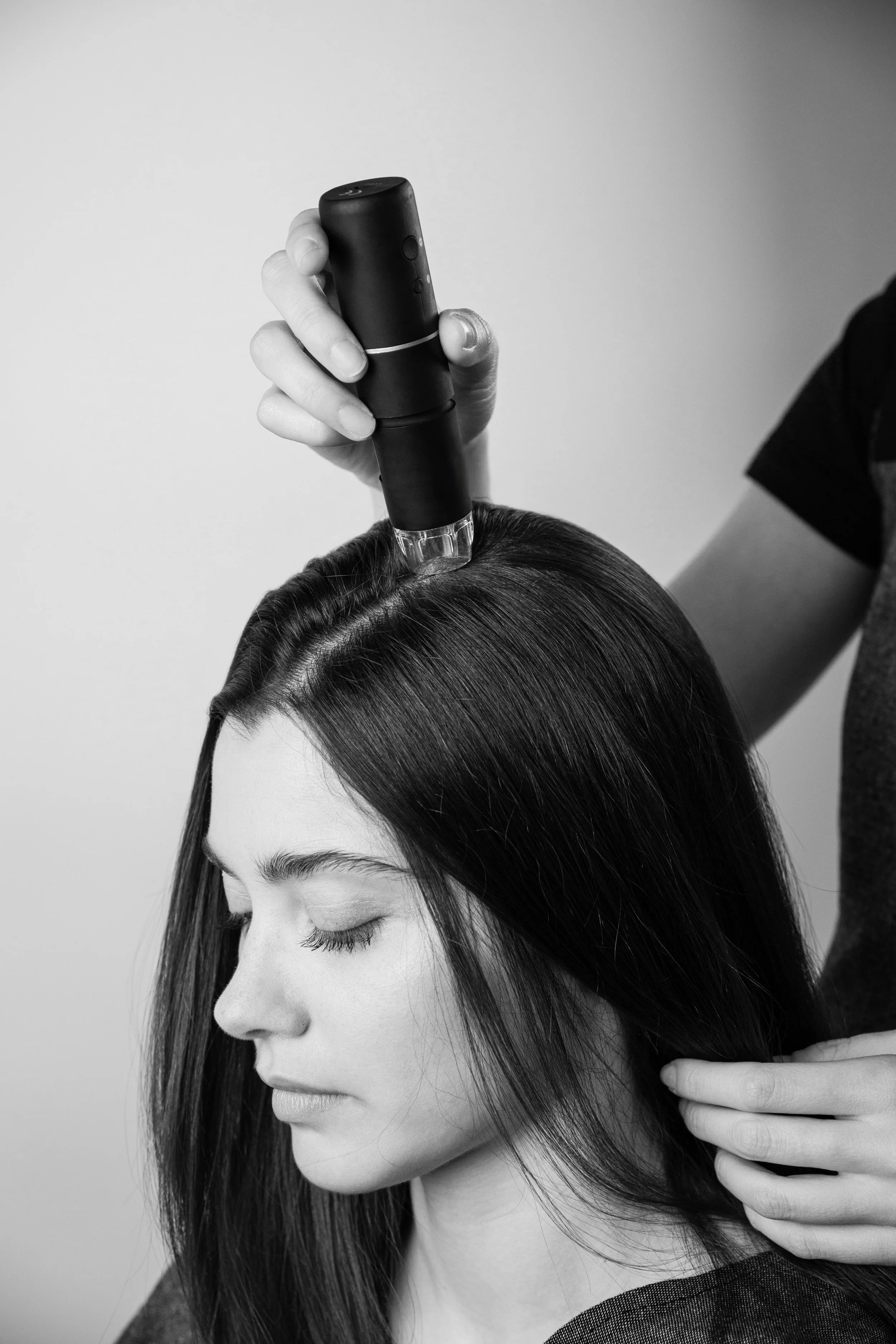 Una donna con i capelli lunghi e lisci, con gli occhi chiusi, si sottopone ad un'analisi con dermocamera sul cuoio capelluto prima del trattamento  riequilibrante head spa