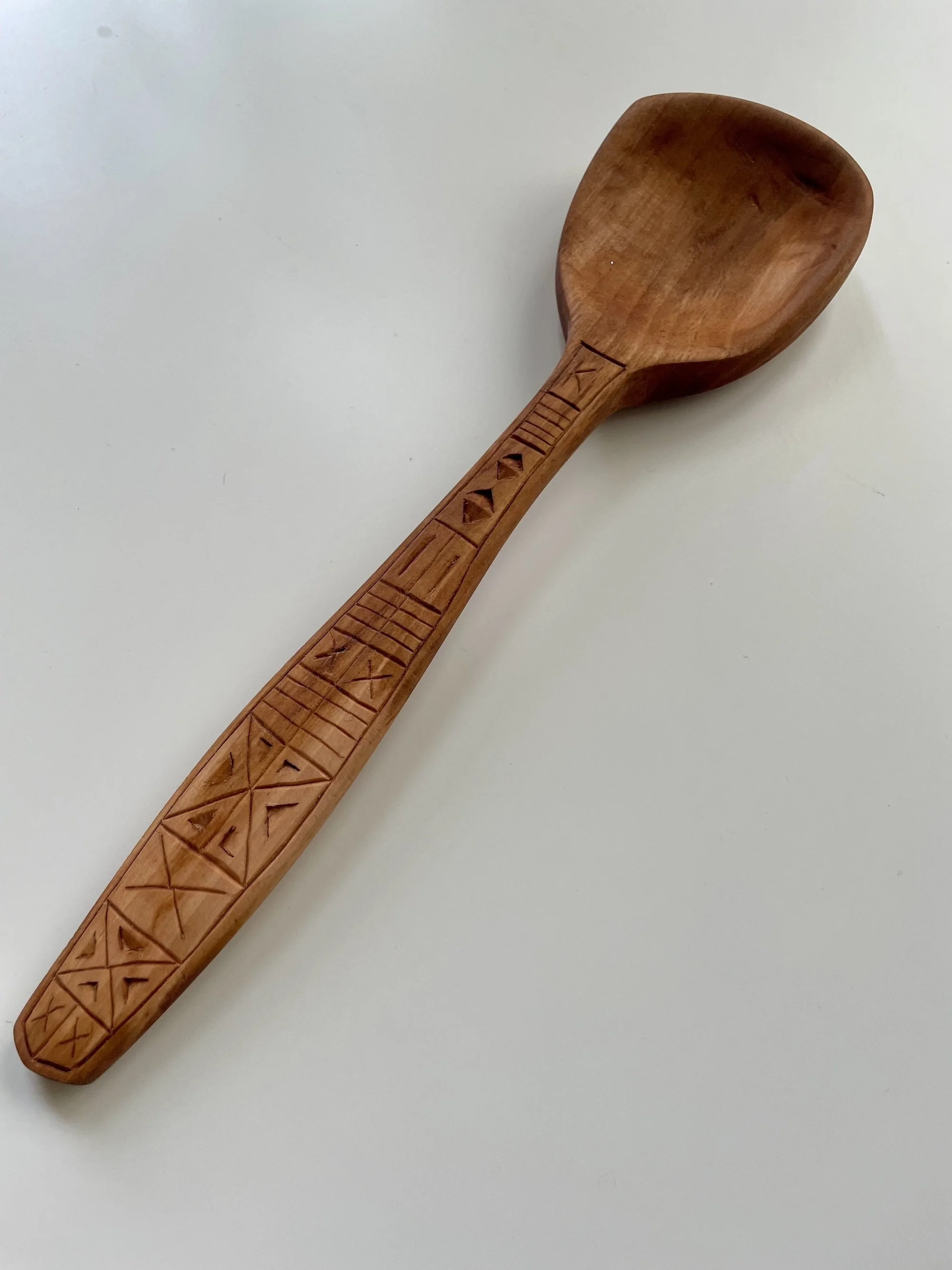 Pear cooking spoon with lines and chip-carved triangles.