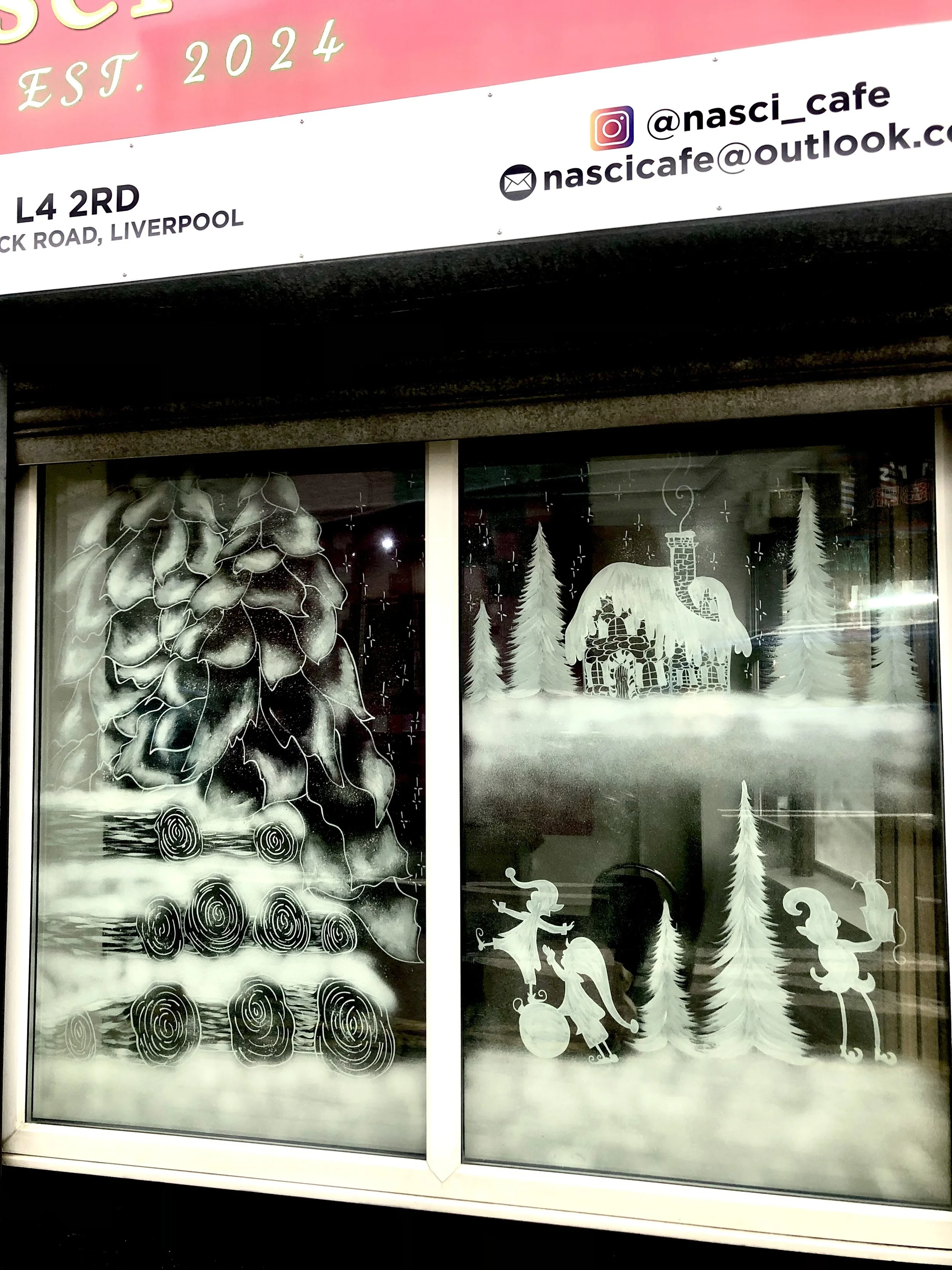 Christmas themed window decorations featuring a pine tree, a house with a chimney, a elf or fairy with a broom, a gnome, and a squirrel, all in white on frosted glass.