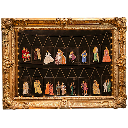 Collection of small vintage style dolls dressed in elaborate period costumes displayed in a gold ornate frame.