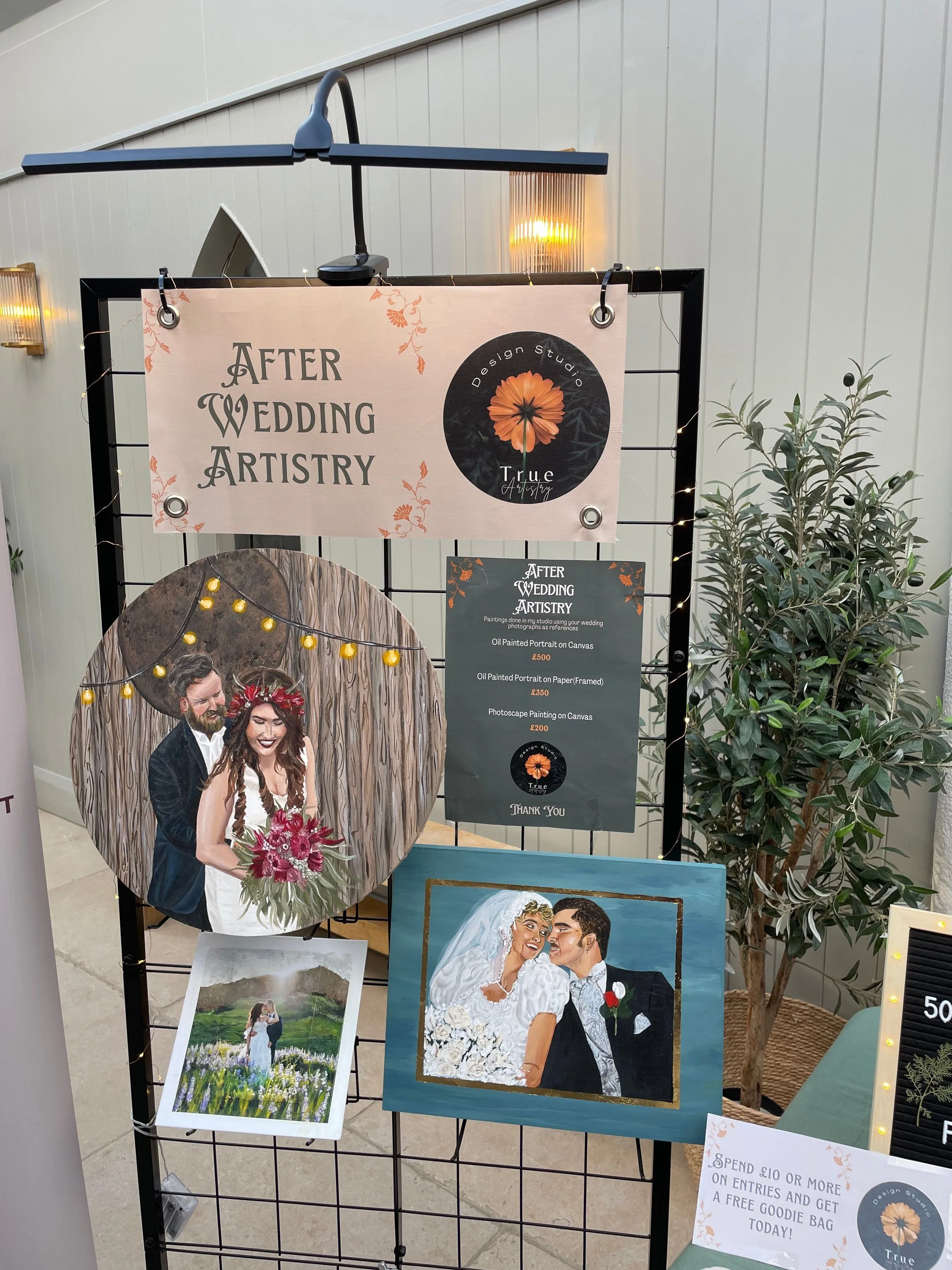 Display board for after wedding artistry with paintings, a photo of a bride and groom, and an advertisement for artistic services.