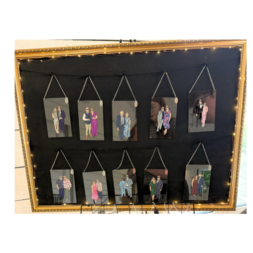 Display of live wedding illustrations hanging on a black background with a gold border and string lights.
