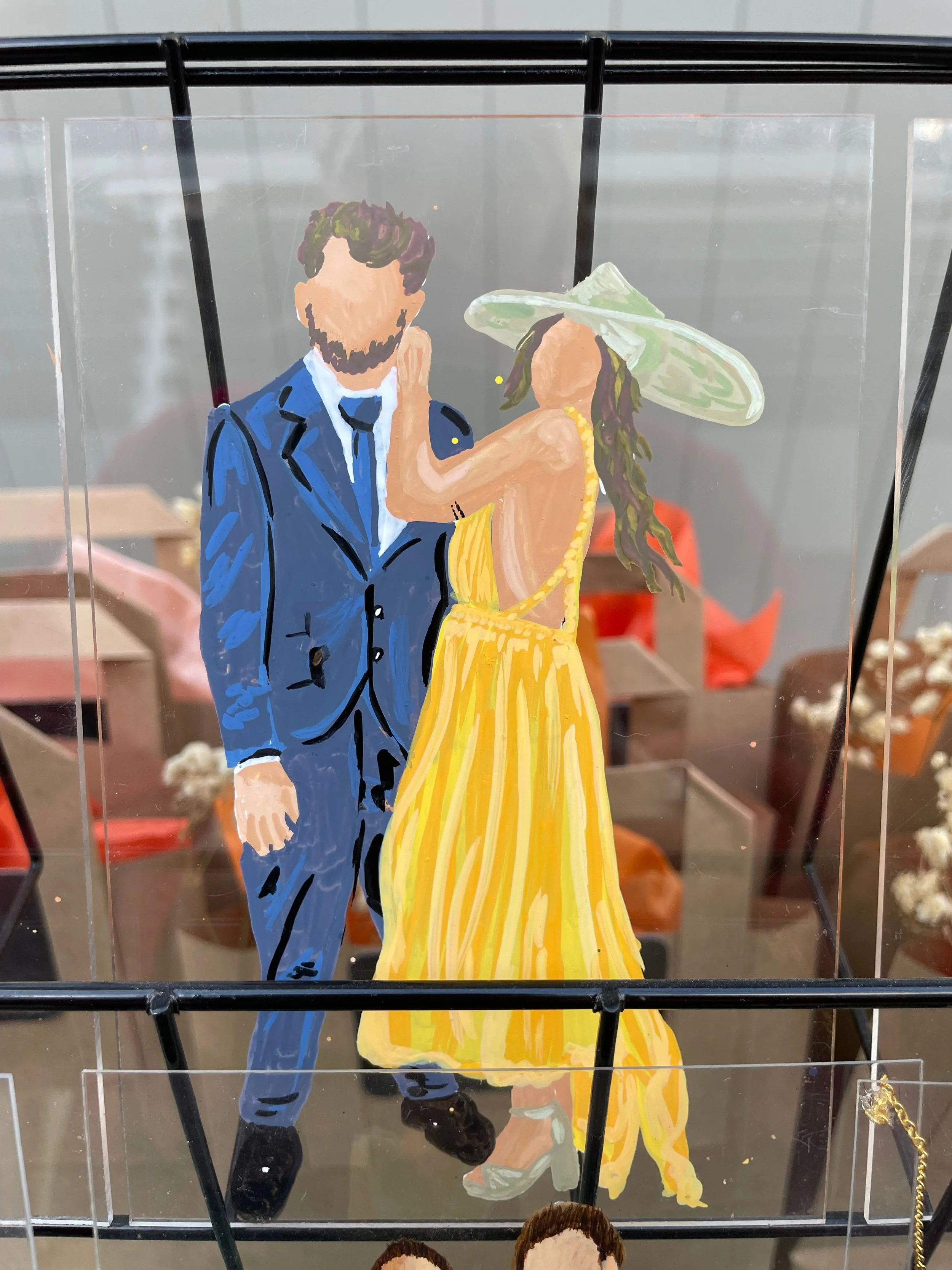 A painted illustration of a man in a blue suit and a woman in a yellow dress and green wide-brimmed hat, embracing each other.