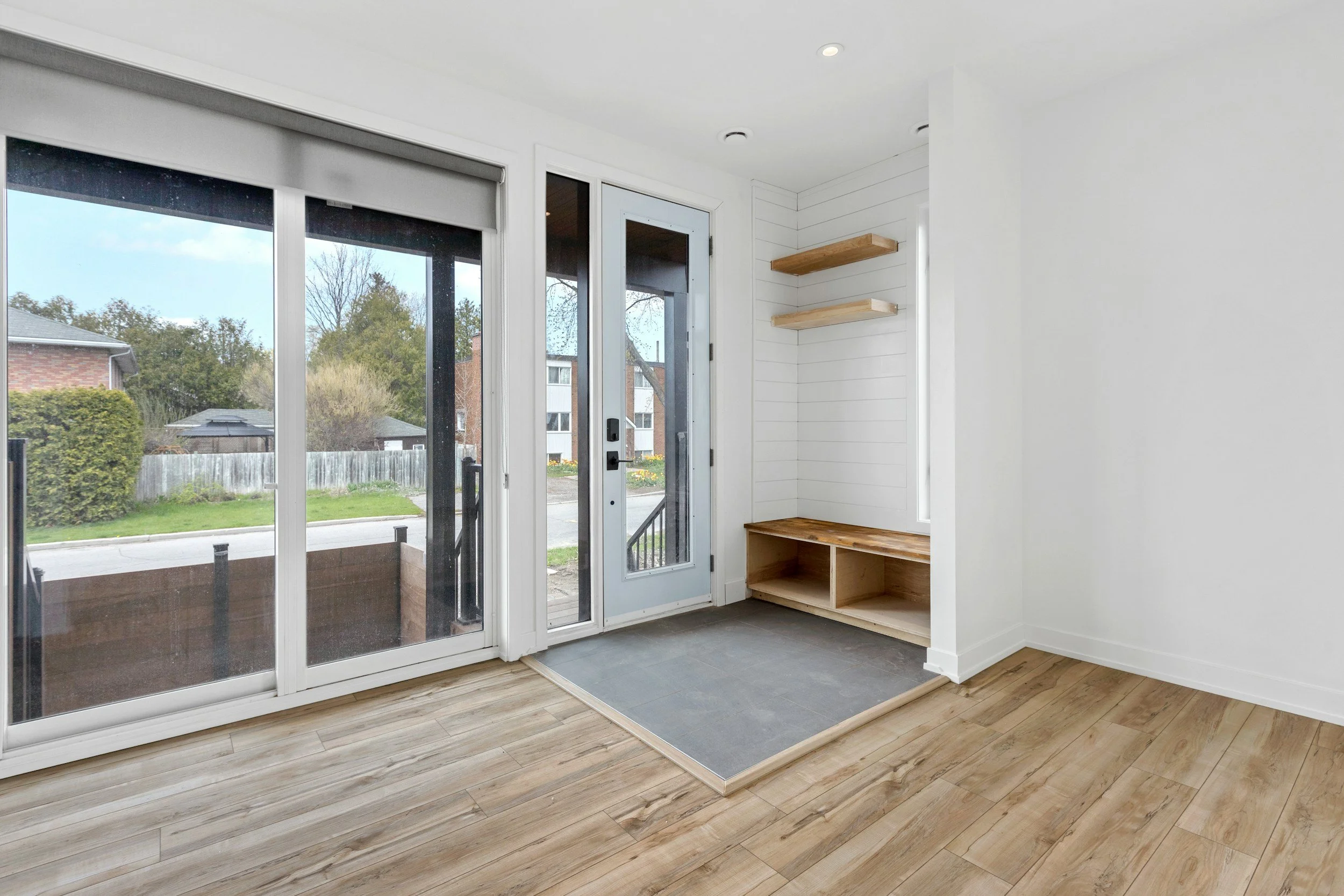 Empty room with large sliding glass doors, wood flooring, and built-in wooden shelves