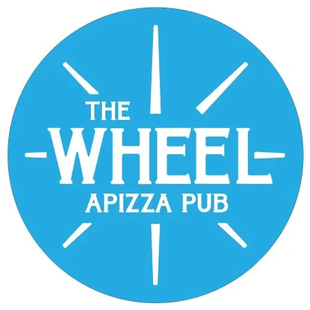 Logo for The Wheel Apizza Pub featuring a blue circle with clock-like markings and white text