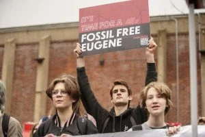 Protesters holding a sign that says 'Fossil Free Eugene' during an environmental rally.
