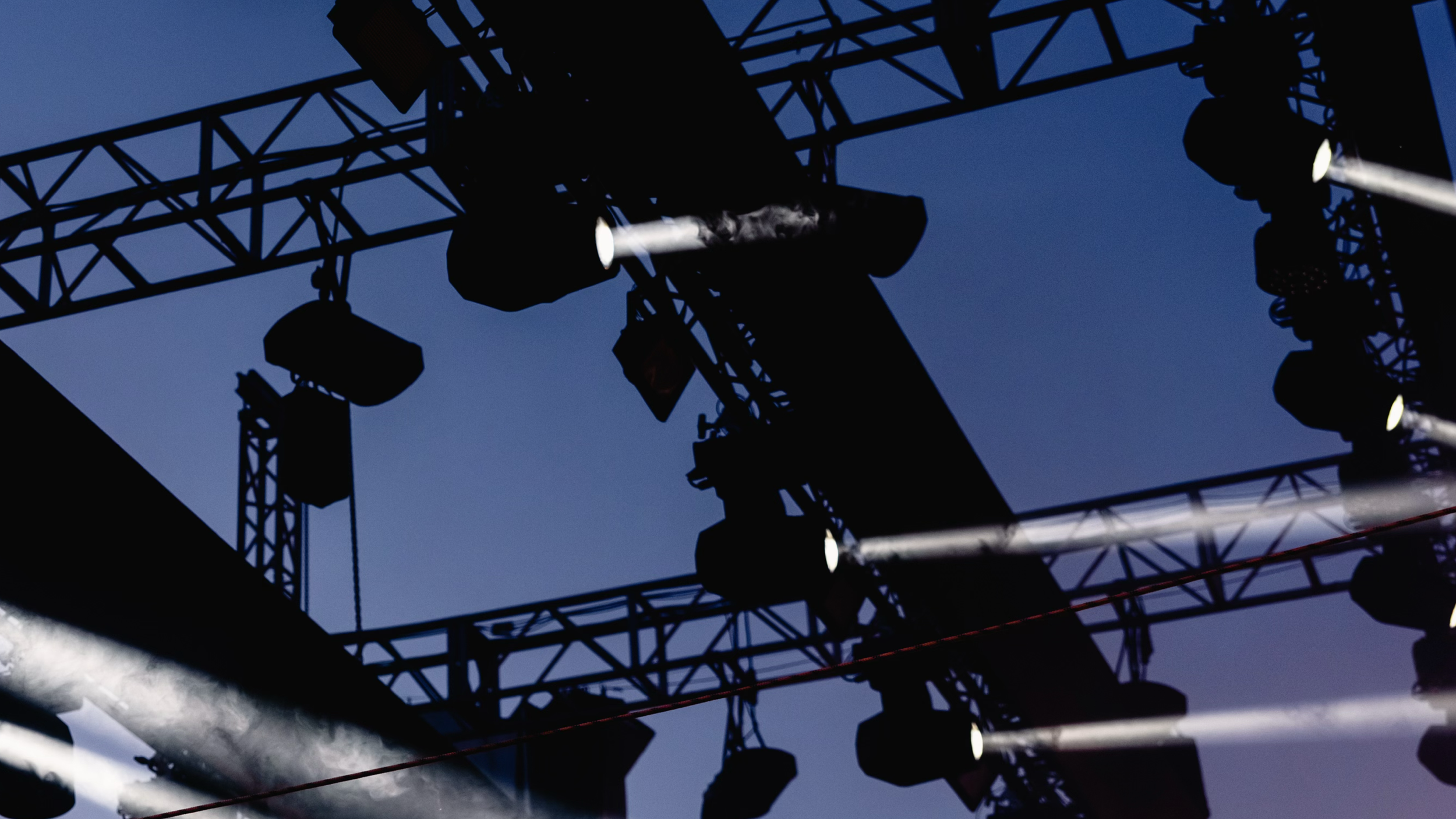 Luces y equipos de sonido en un escenario de concierto con cielo nocturno de fondo.
