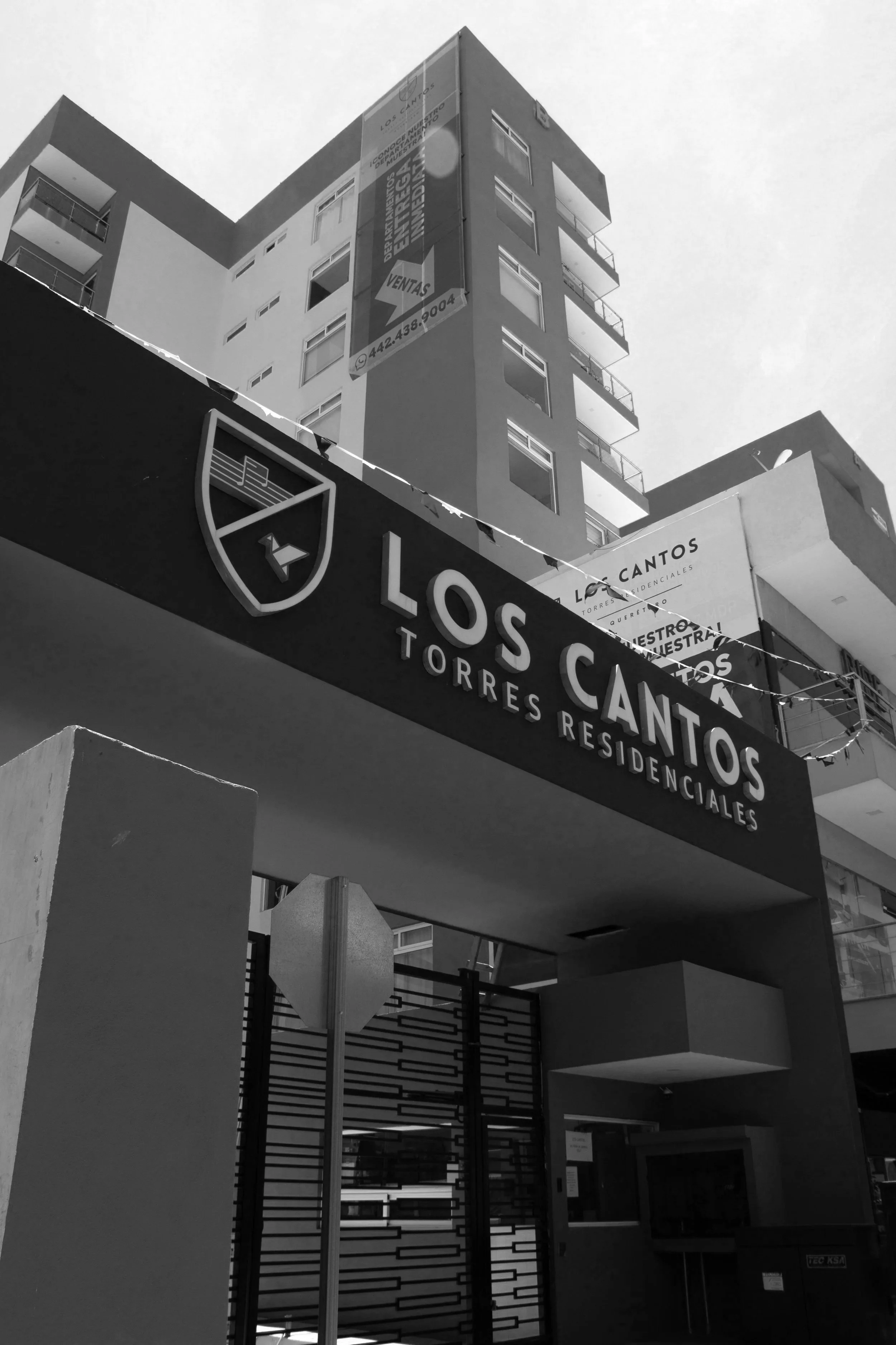 Edificio residencial llamado Los Cantos Torres Residenciales con señal de entrada y anuncios en la fachada, en una ciudad