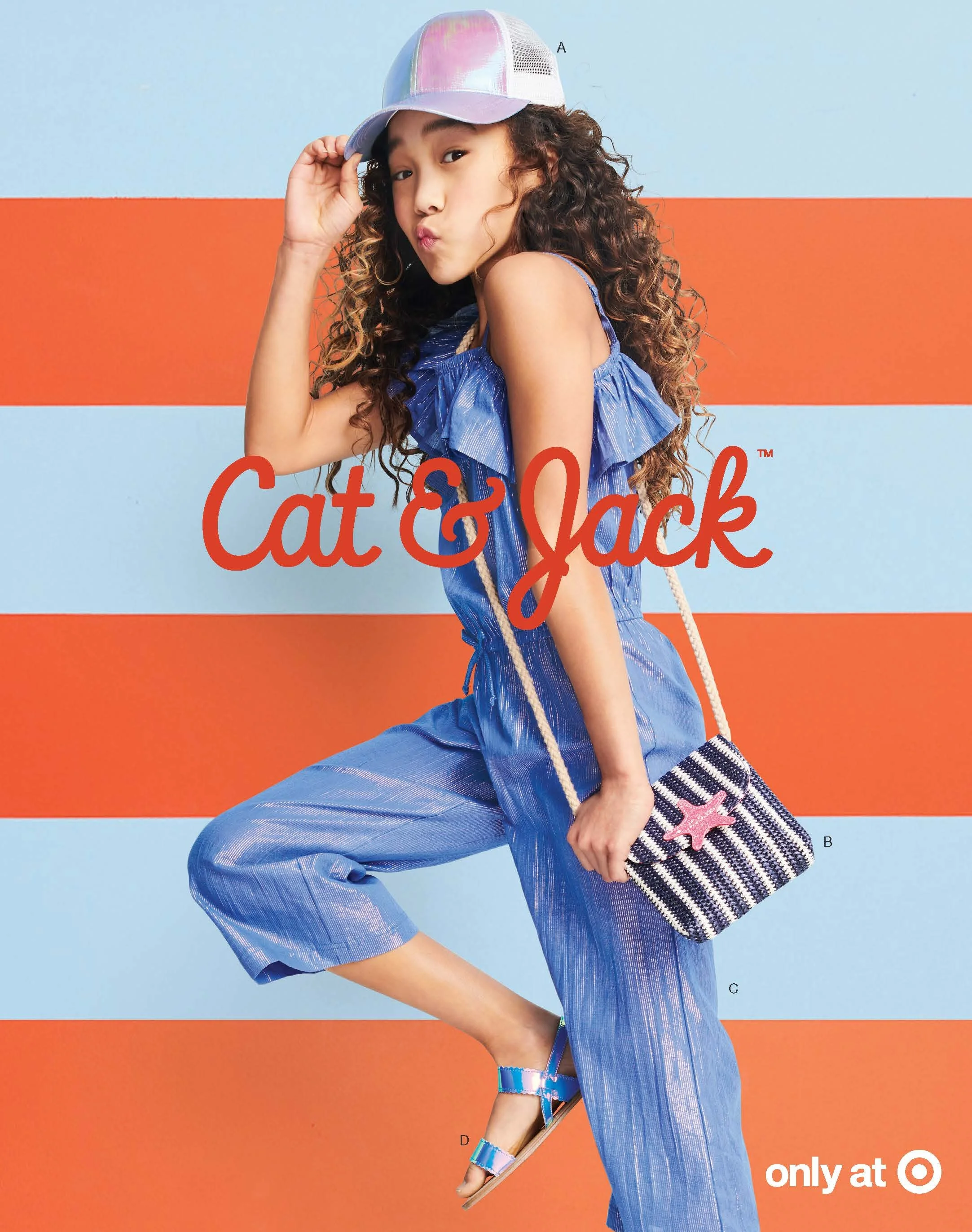 A young girl with curly brown hair, wearing a shiny, iridescent cap and a matching shiny blue off-the-shoulder dress, stands against a background featuring horizontal stripes of light blue and orange. She is holding a striped tote bag with a star emb