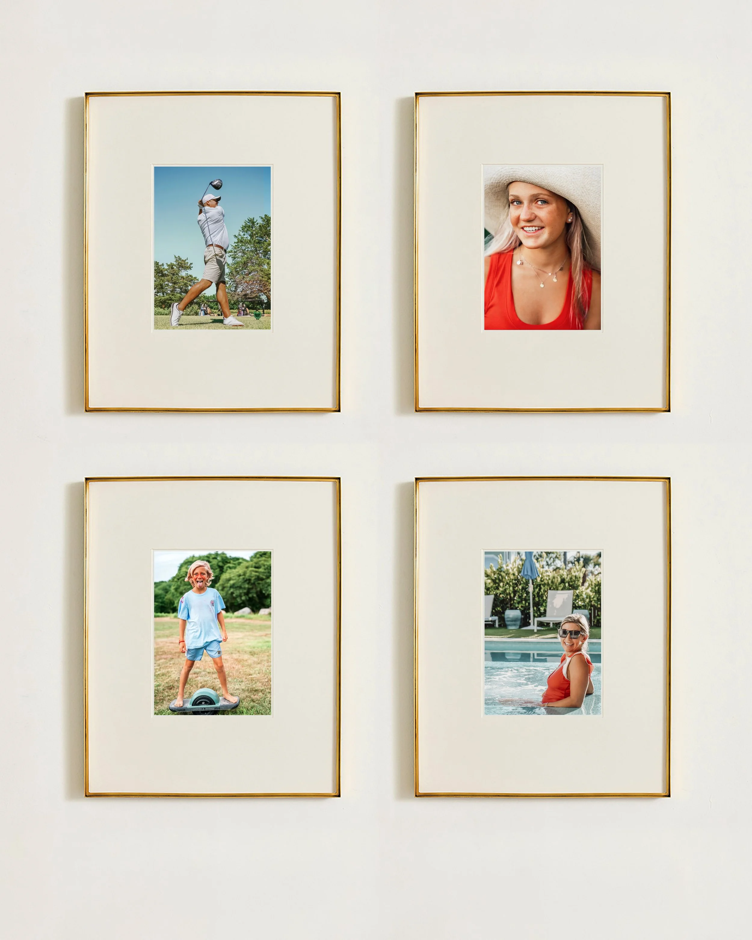 Four framed photographs hanging on a light-colored wall, each showing people outdoors, including a woman in a red top and sun hat, and a girl playing in a park.
