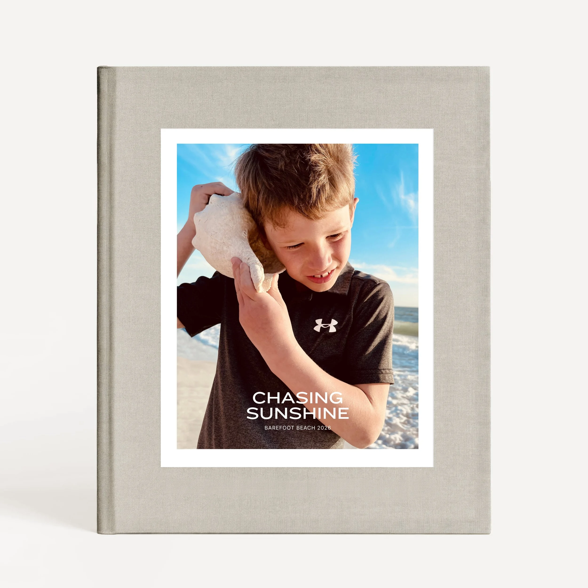 A book cover titled 'Chasing Sunshine' with a photo of a boy with red hair holding a seashell to his ear at the beach, with blue sky and ocean in the background.