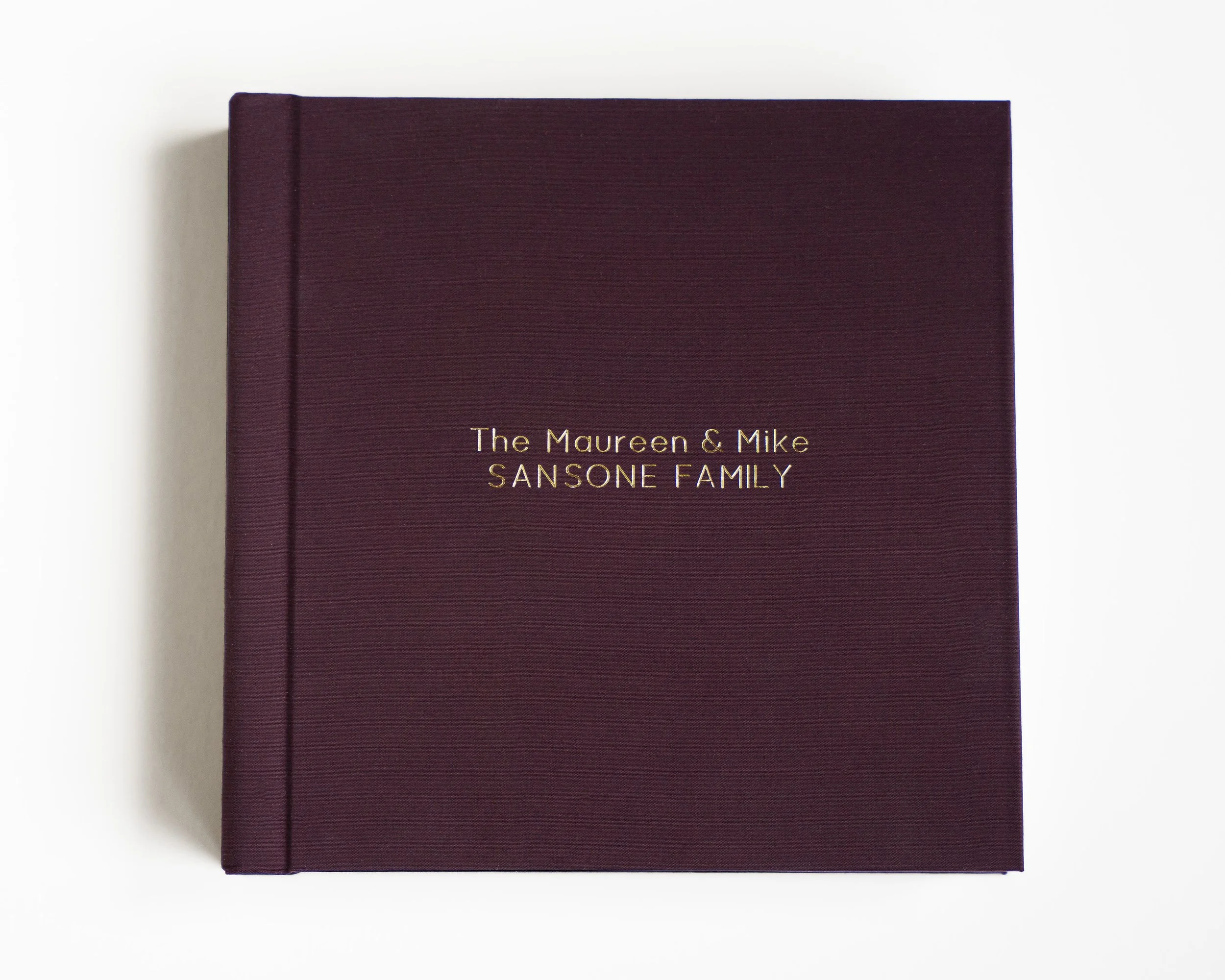 Close-up of a dark maroon hardcover book with gold embossed text on the cover, placed on a white background.
