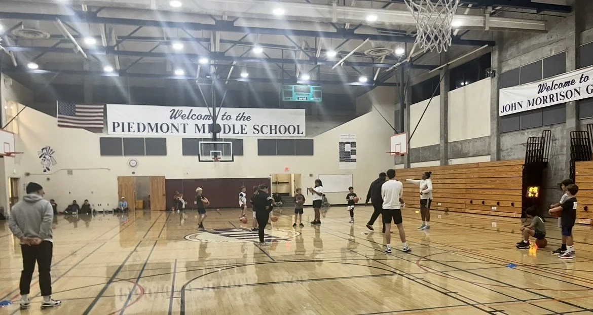 Basketball practice or class at Piedmont Middle School gymnasium with students, teachers, and basketballs.