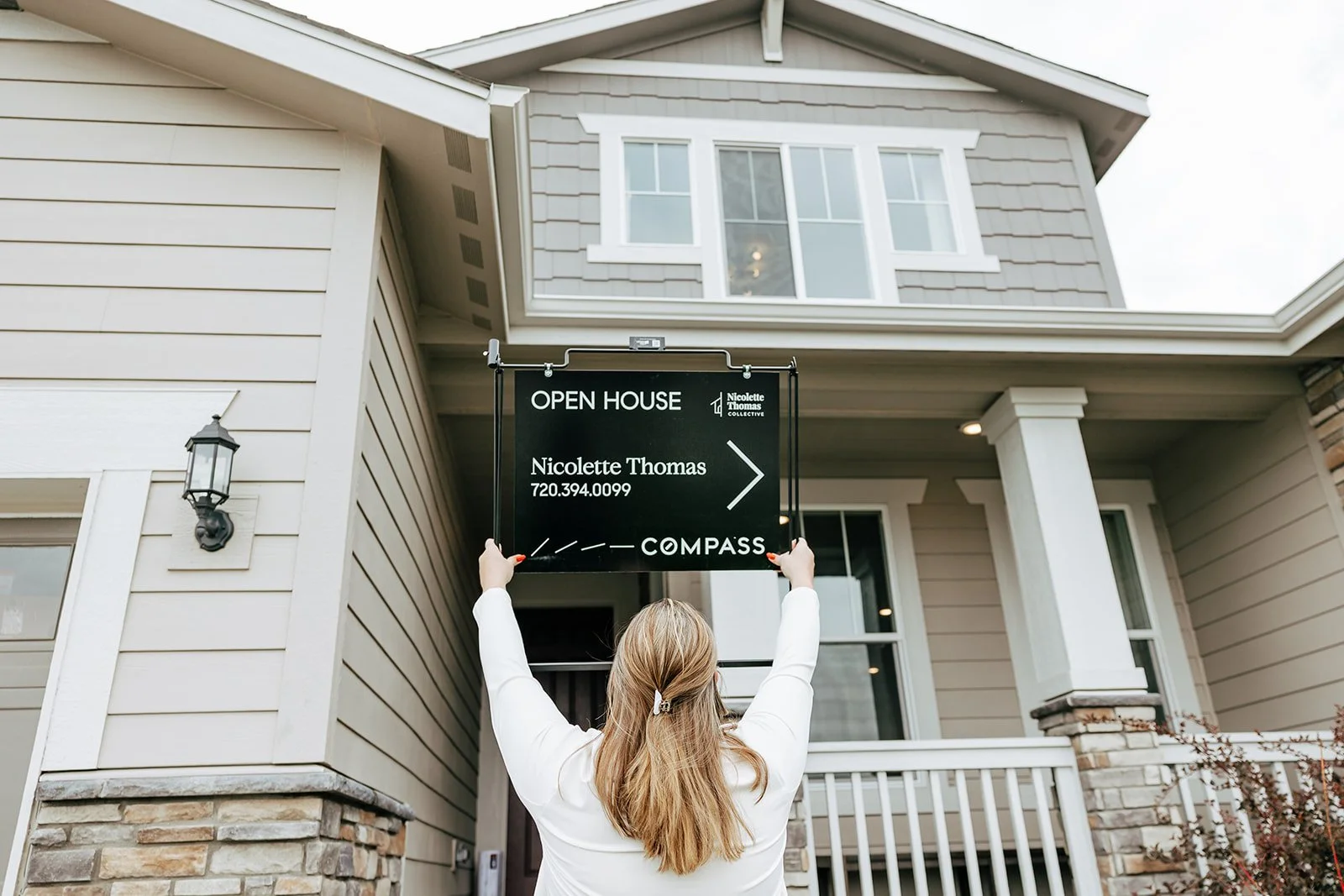 Realtor in Colorado standing in front of a home for sale, holding an Open House sign for Nicolette Thomas